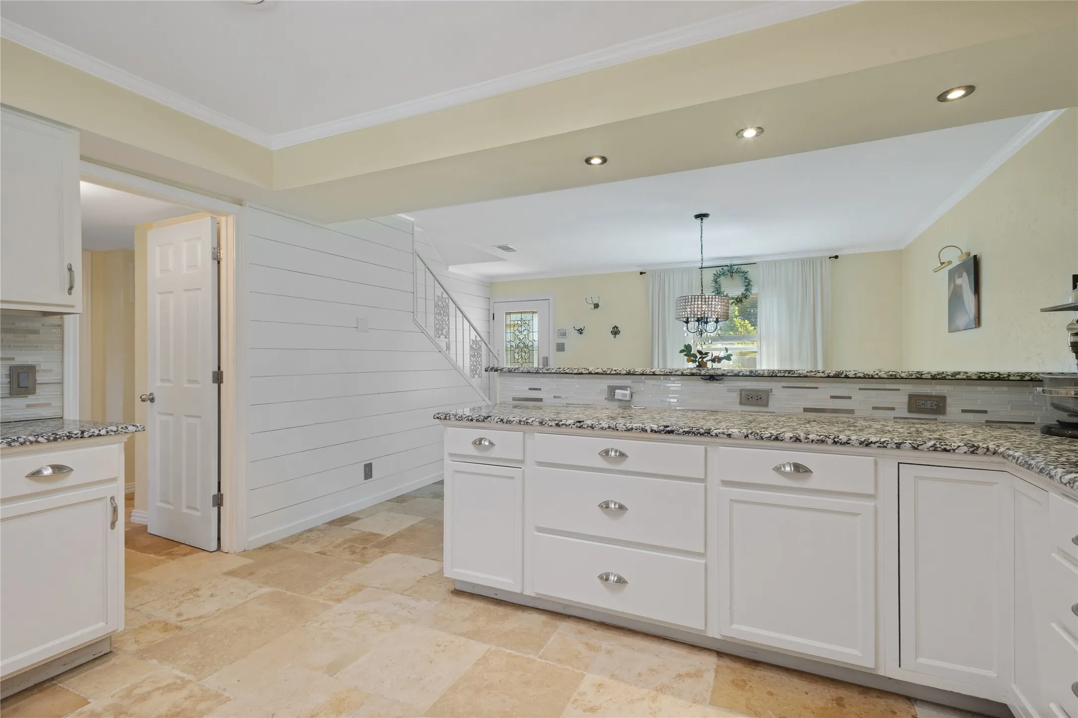 White cabinetry with polished hardware, granite-style countertops, mosaic tile backsplash, recessed lighting, and large format floor tiles