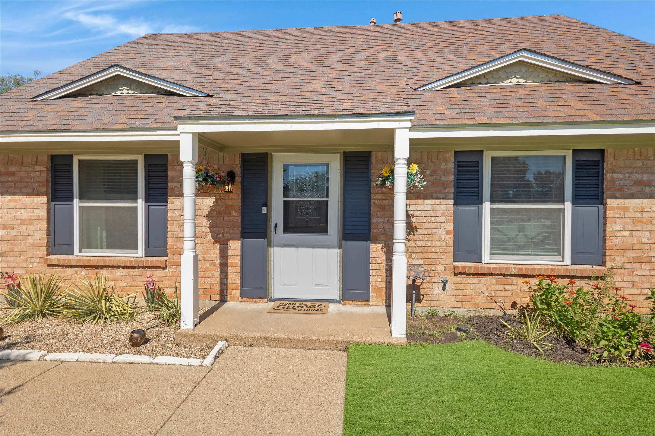 Brick exterior with a covered entry, gabled roofline, and louvered window shutters
