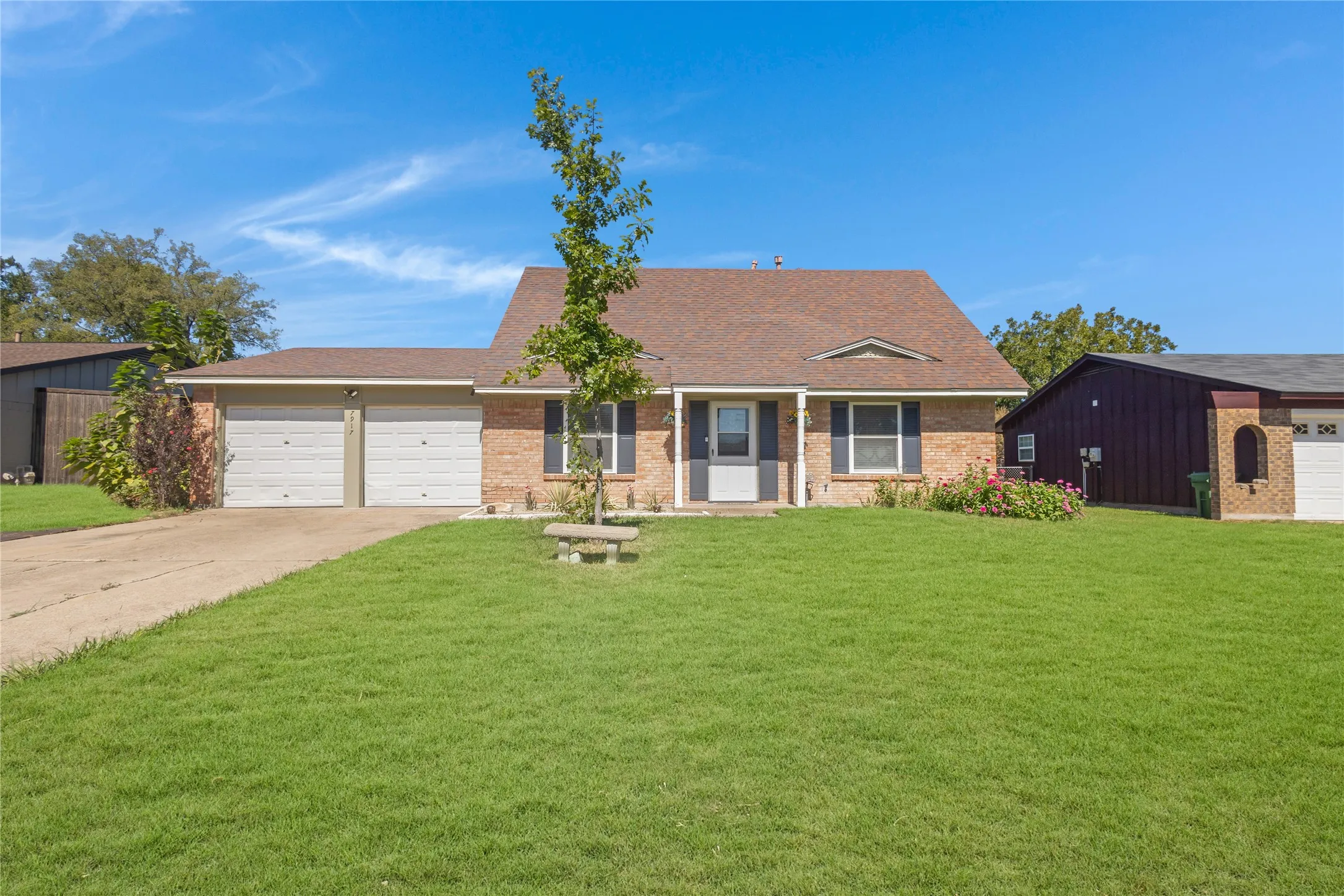 Brick exterior with a brown shingle roof, featuring dual garage doors and a paved driveway