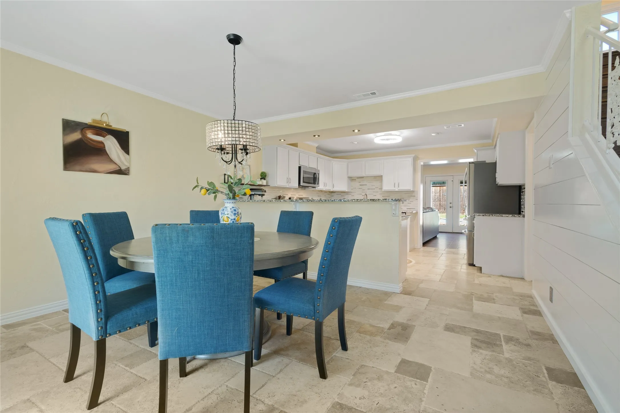 Recessed lighting and a decorative chandelier illuminate the dining area