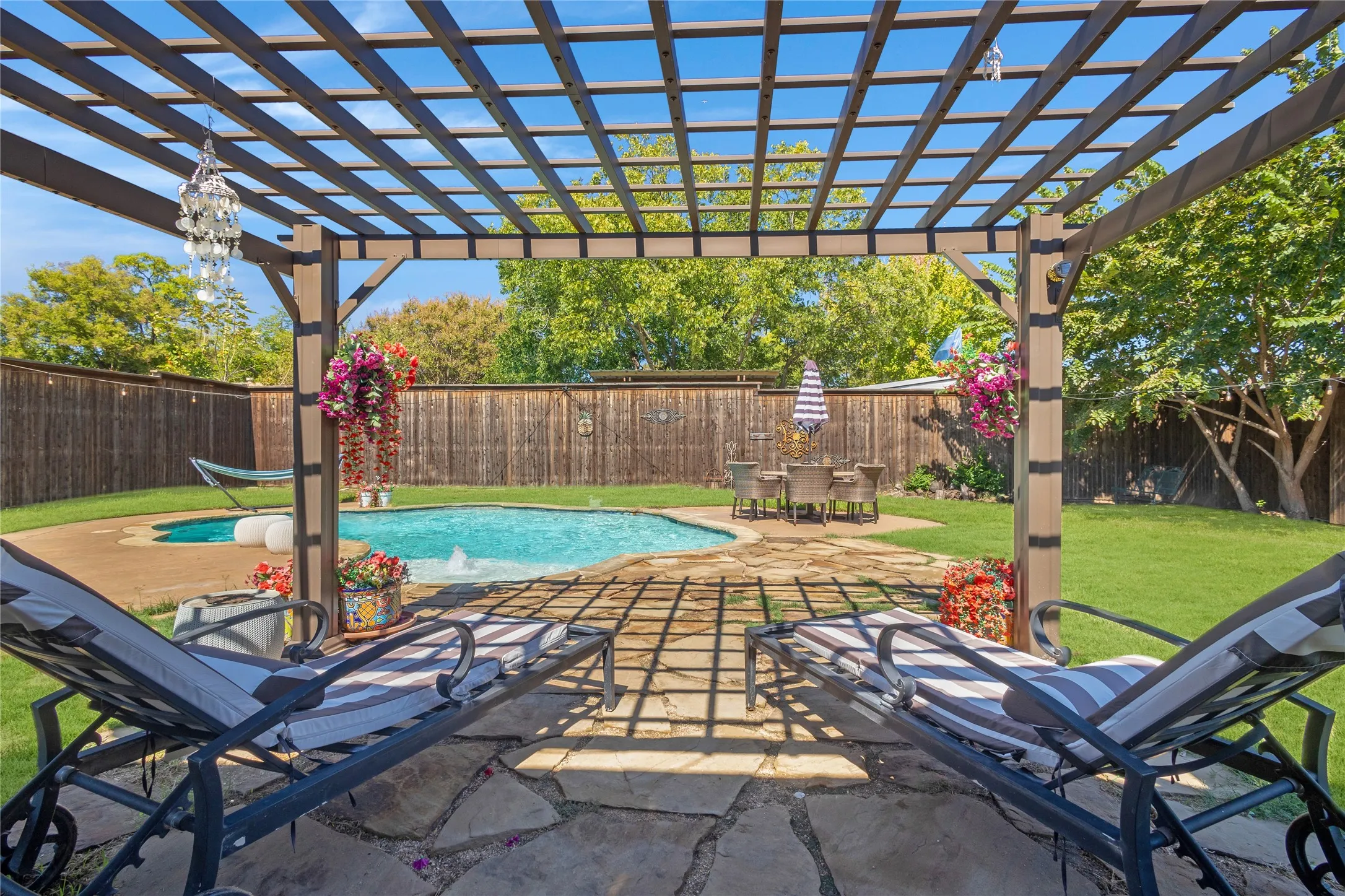 Expansive backyard featuring a pergola, flagstone patio, in-ground swimming pool, and a wooden privacy fence