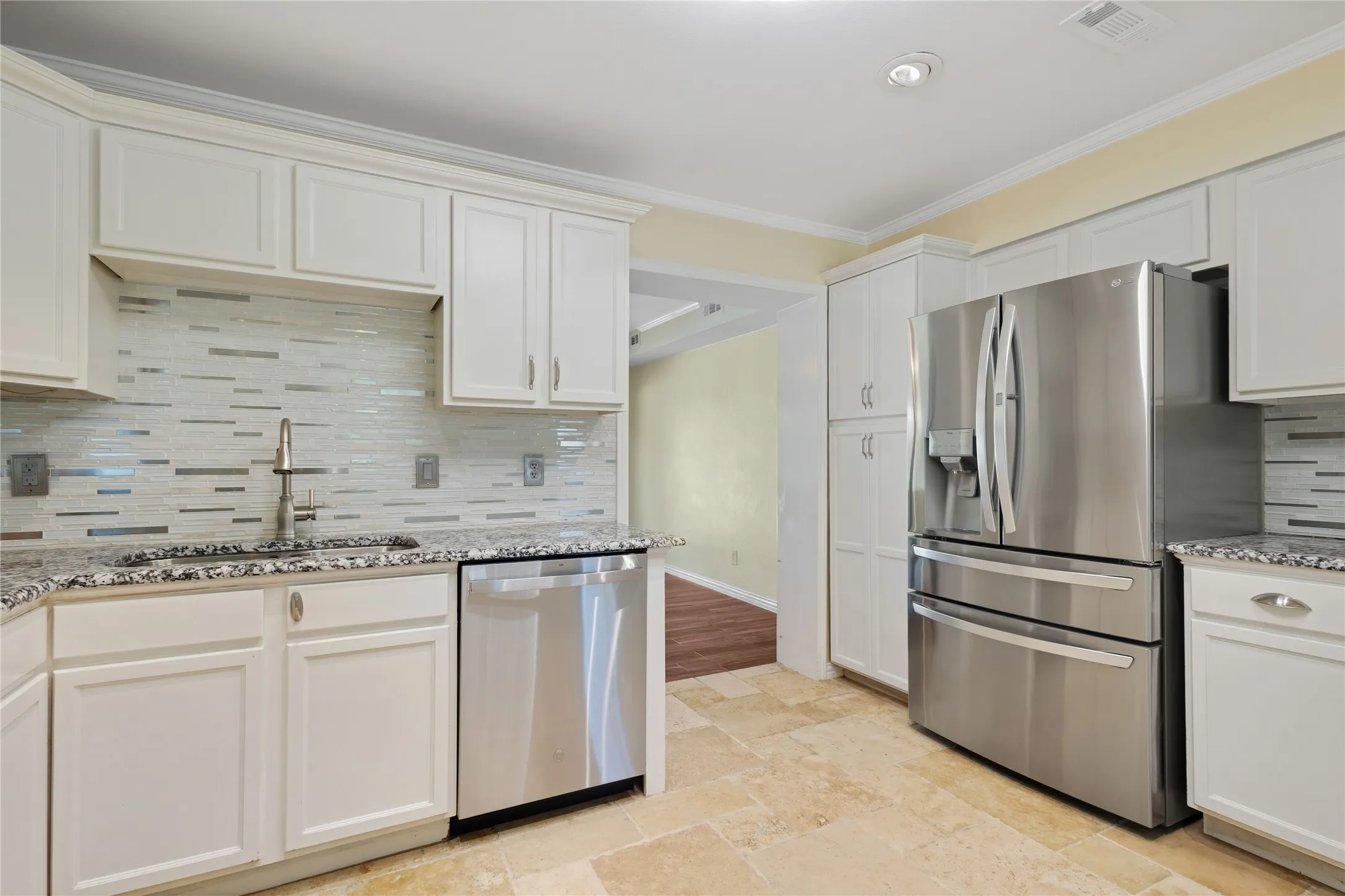 Kitchen with white shaker-style cabinetry, stainless steel appliances, speckled stone countertops, and a mosaic tile backsplash