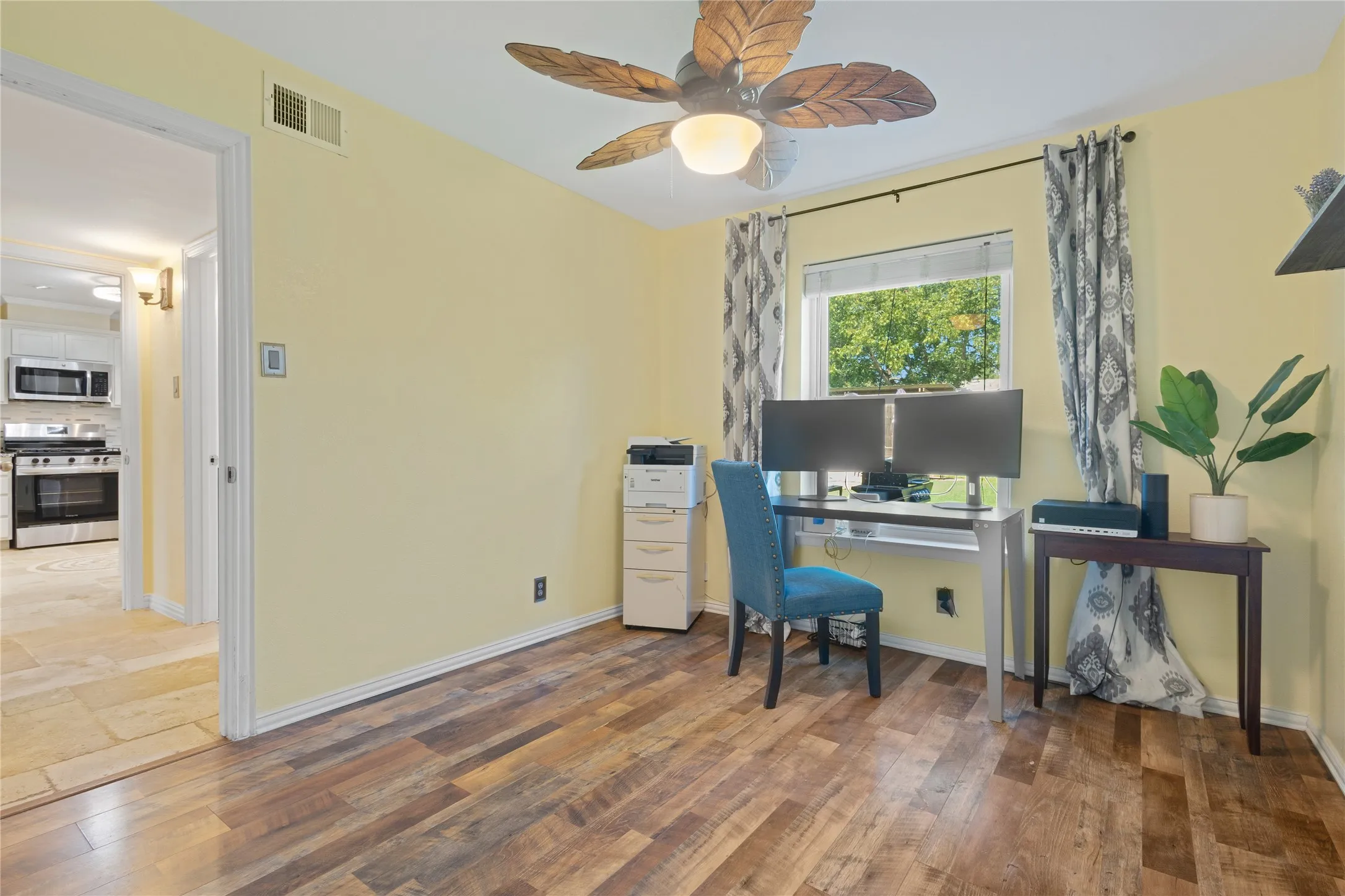 Wood-finish flooring with light yellow walls and a ceiling fan