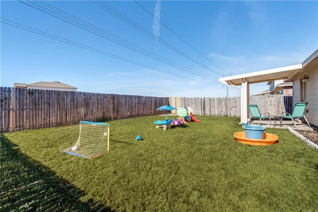 Expansive backyard featuring a covered patio, established lawn, and a wood privacy fence