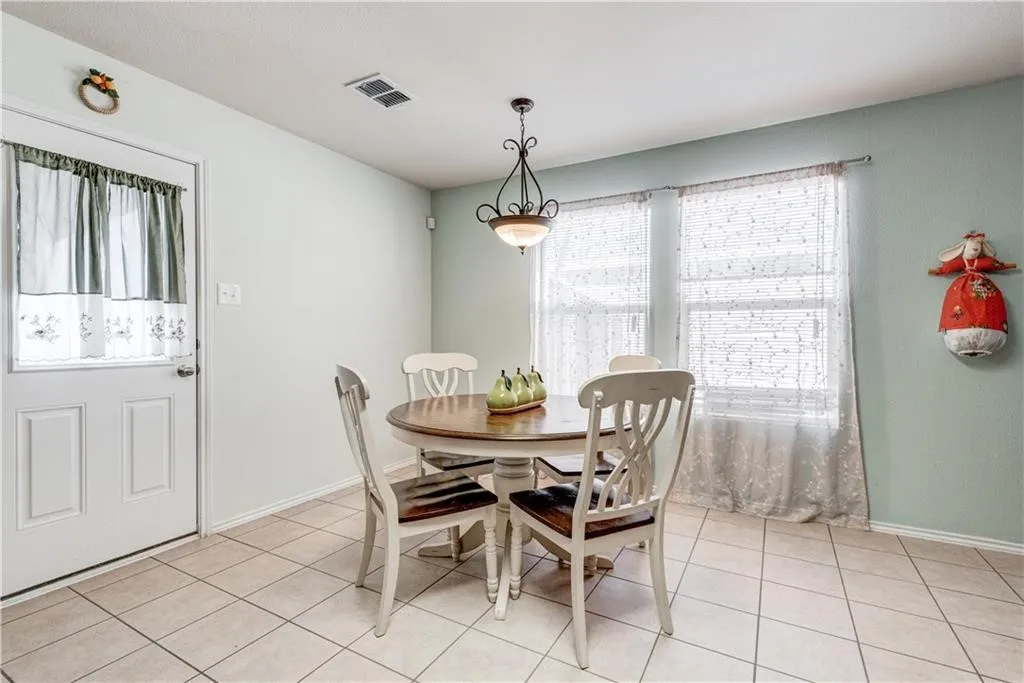 Tile flooring, multiple windows, pendant lighting, and a white paneled door