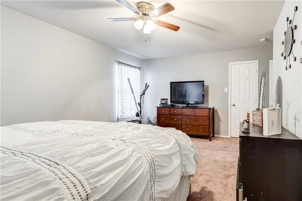 Ceiling fan with light kit, neutral wall paint, white trim, window with patterned blinds, and a white interior door