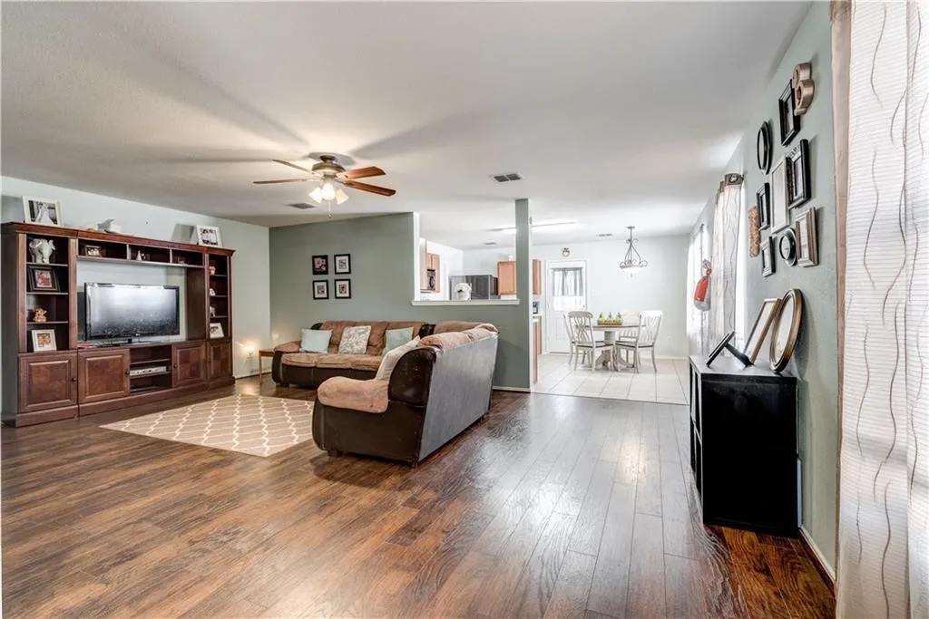 Wood-finish flooring, built-in entertainment center, ceiling fan, recessed lighting, and light-toned wall color