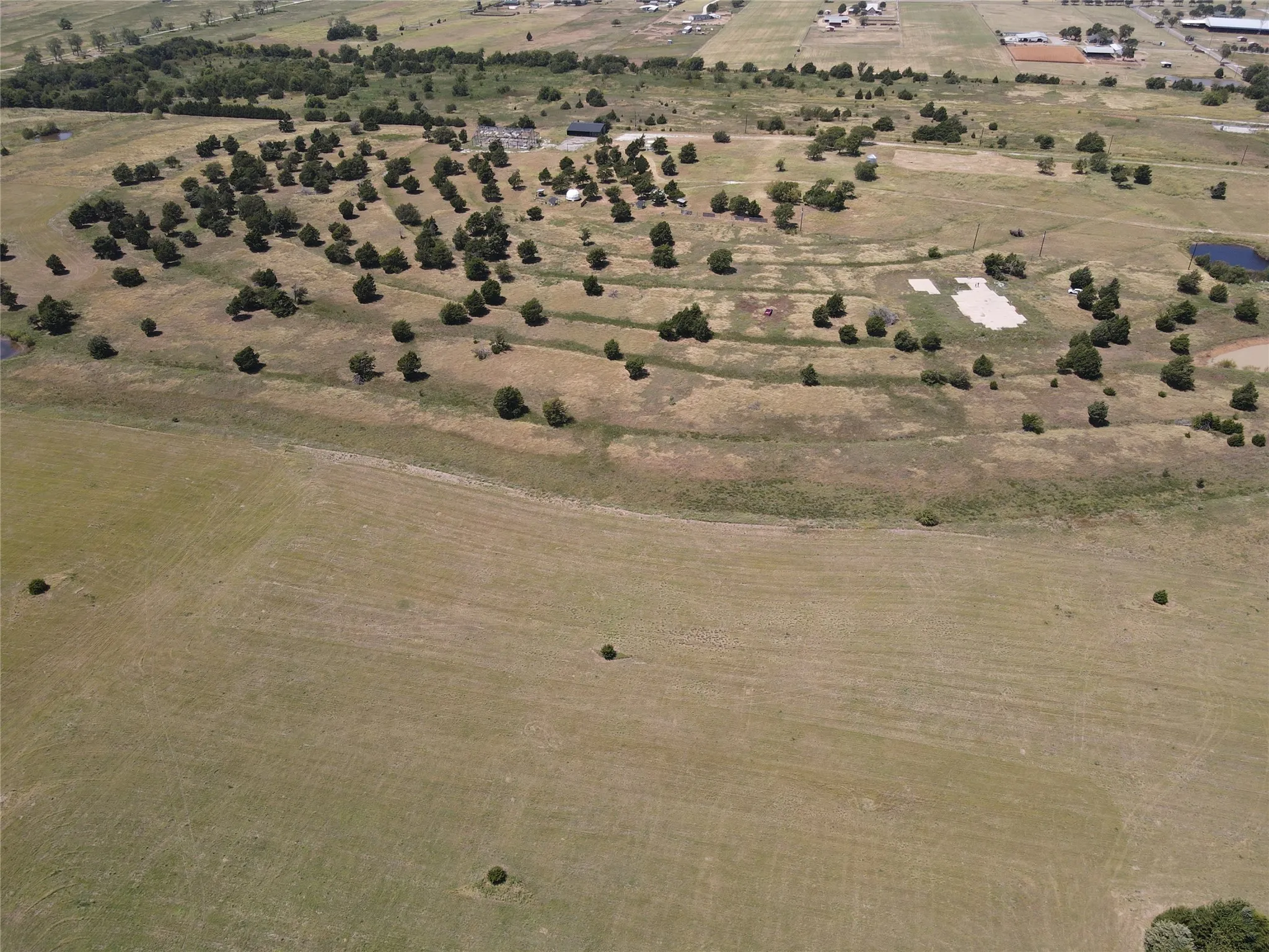 Expansive acreage featuring multiple tiered clearings, scattered mature trees, and a visible pond