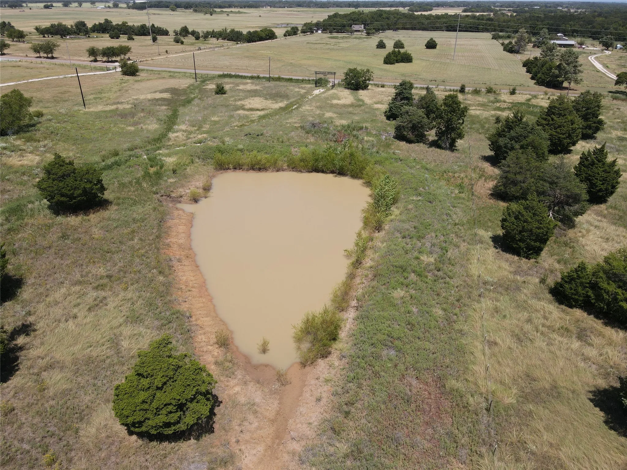 Expansive land featuring a natural pond and scattered trees