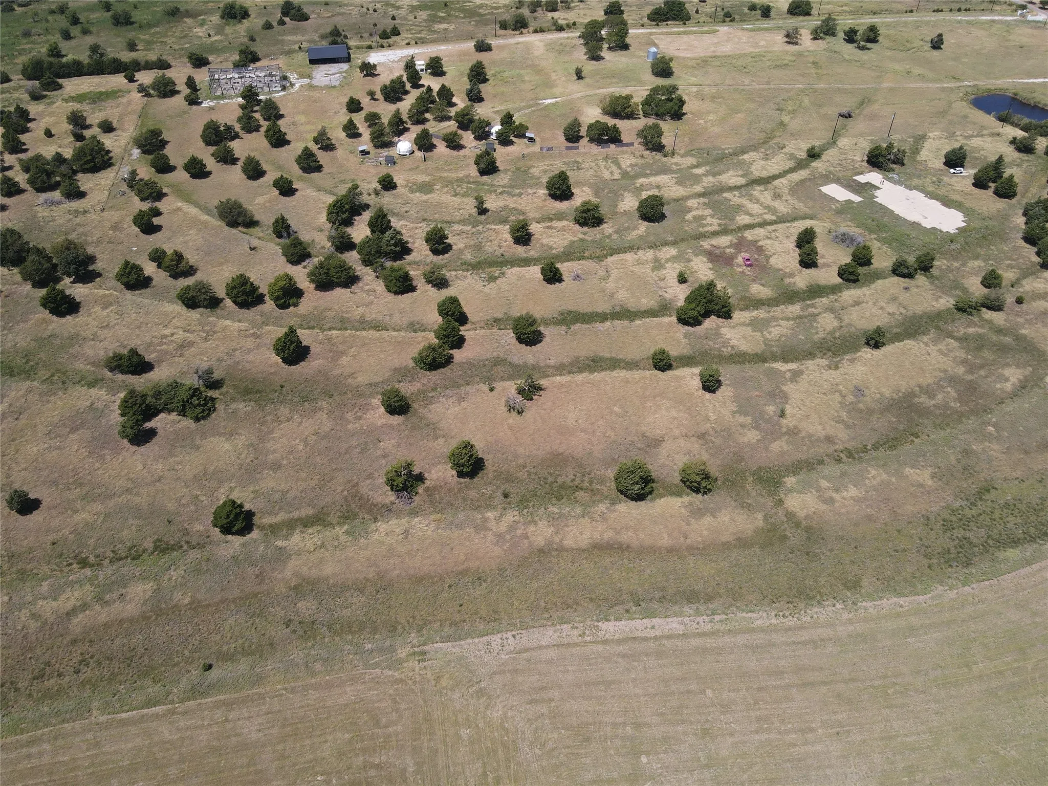 Expansive acreage with terraced landscaping, mature trees, and a visible pond feature
