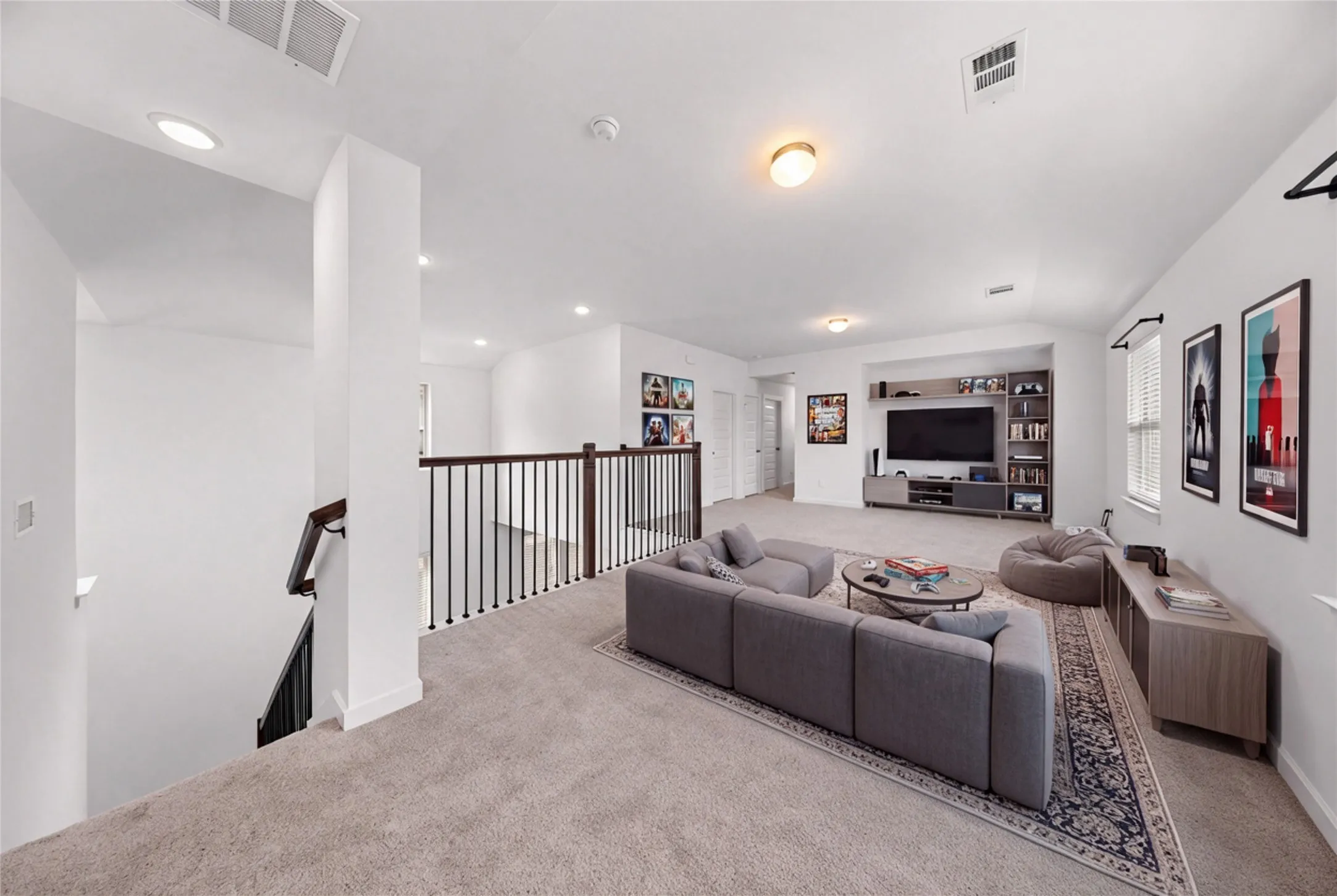 Expansive carpeted loft space featuring built-in media shelving and recessed lighting