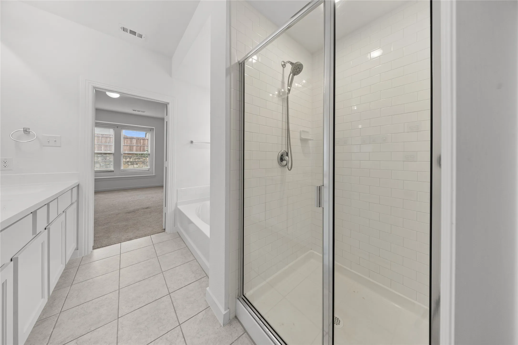 Primary Bathroom with Frameless Glass Shower Enclosure and Subway Tile SurroundSleek primary bathroom featuring a frameless glass shower enclosure with chrome hardware and polished chrome showerhead