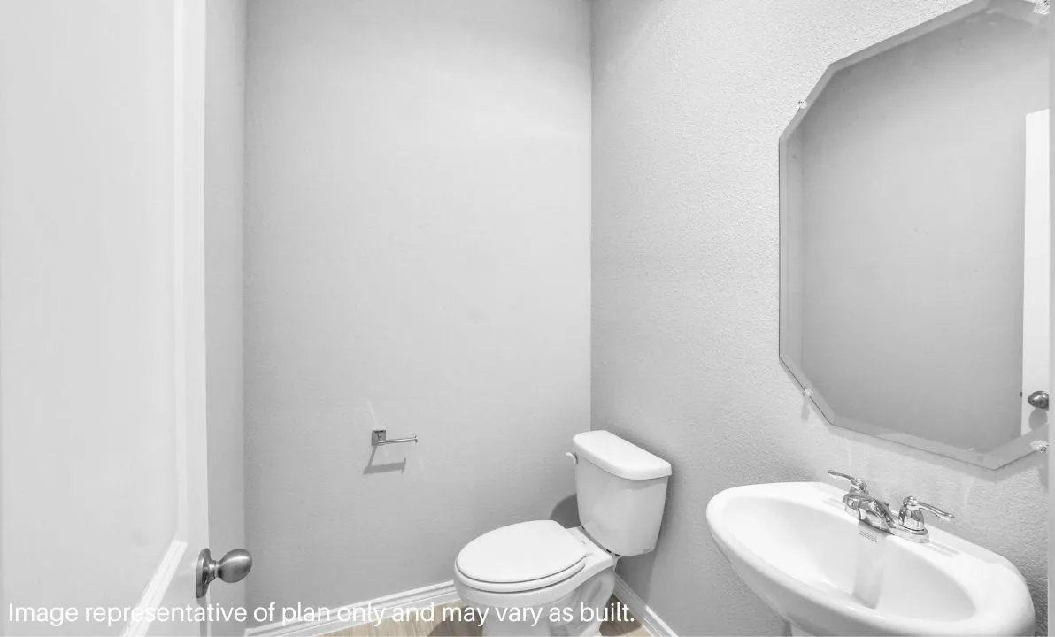 Pedestal sink with chrome fixtures, octagonal frameless mirror, and wood-finish flooring