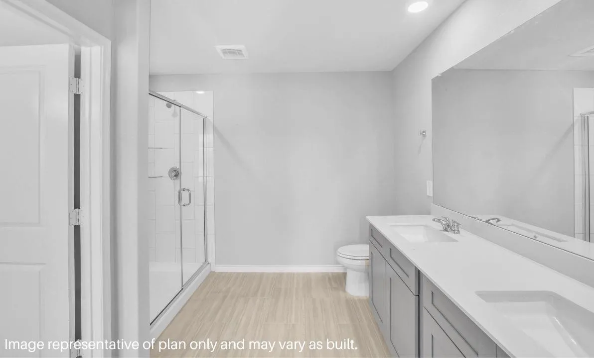 Dual vanity with integrated sinks, glass-enclosed shower, wood-finish flooring, and recessed lighting