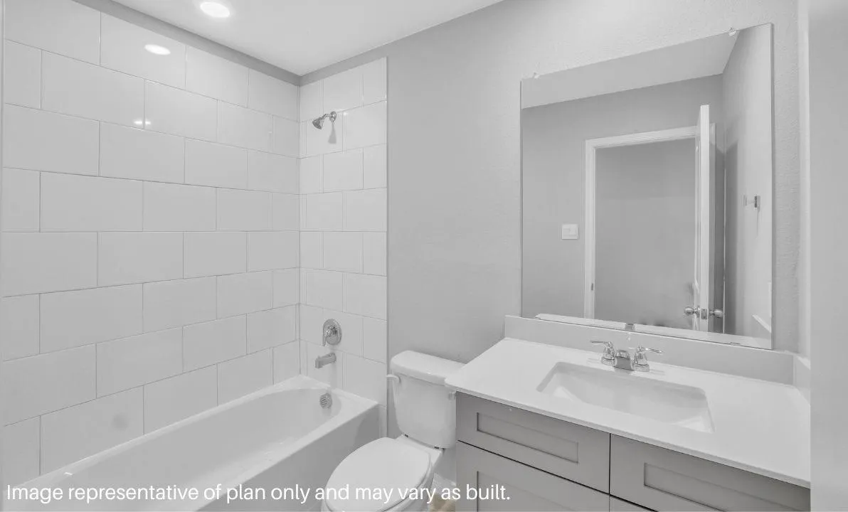 Built-in bathtub with subway tile surround, chrome shower fixtures, vanity with integrated sink, chrome faucet, and expansive wall-mounted mirror