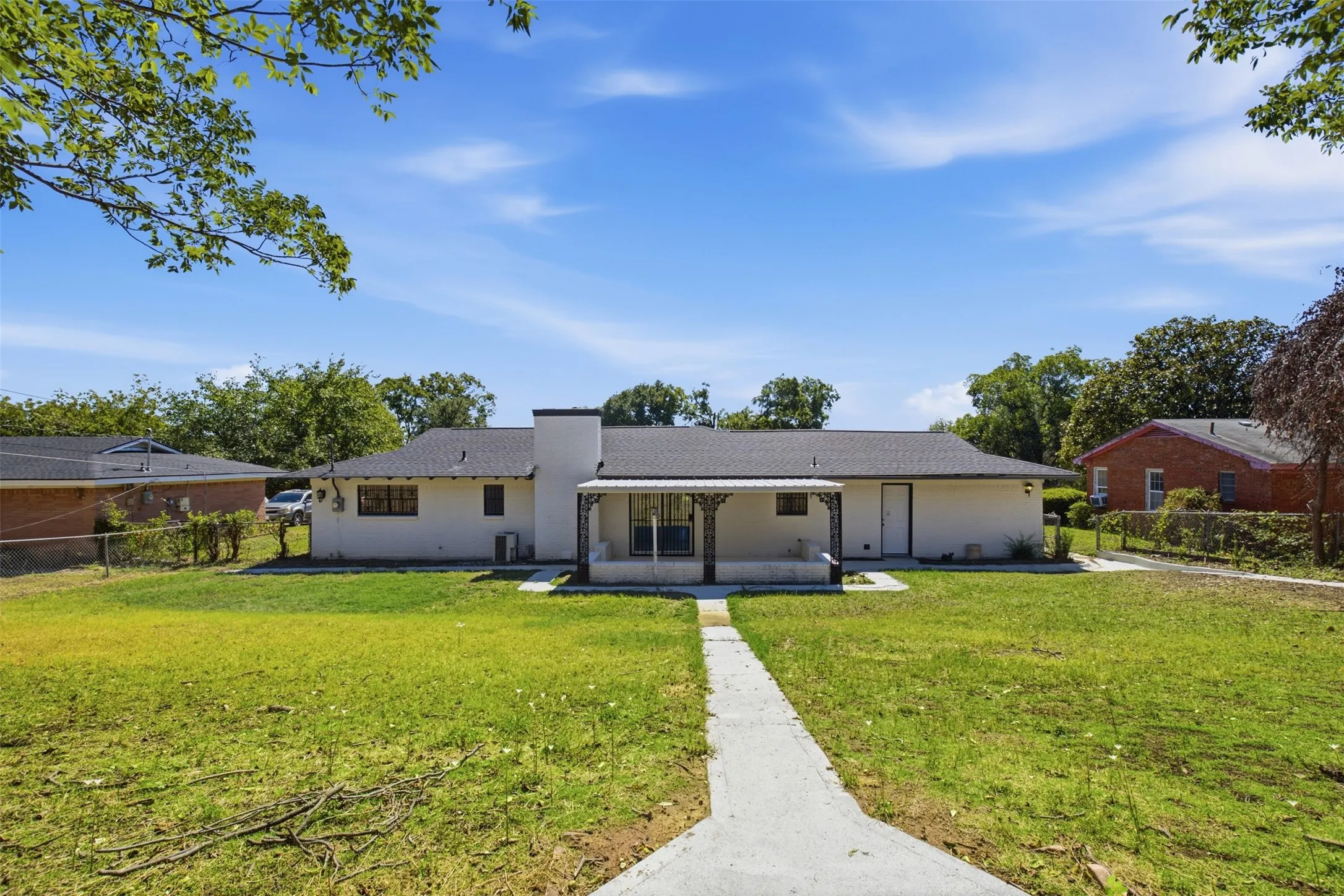 Single-story home featuring a covered front porch with decorative columns, white painted exterior, and a dark shingle roof