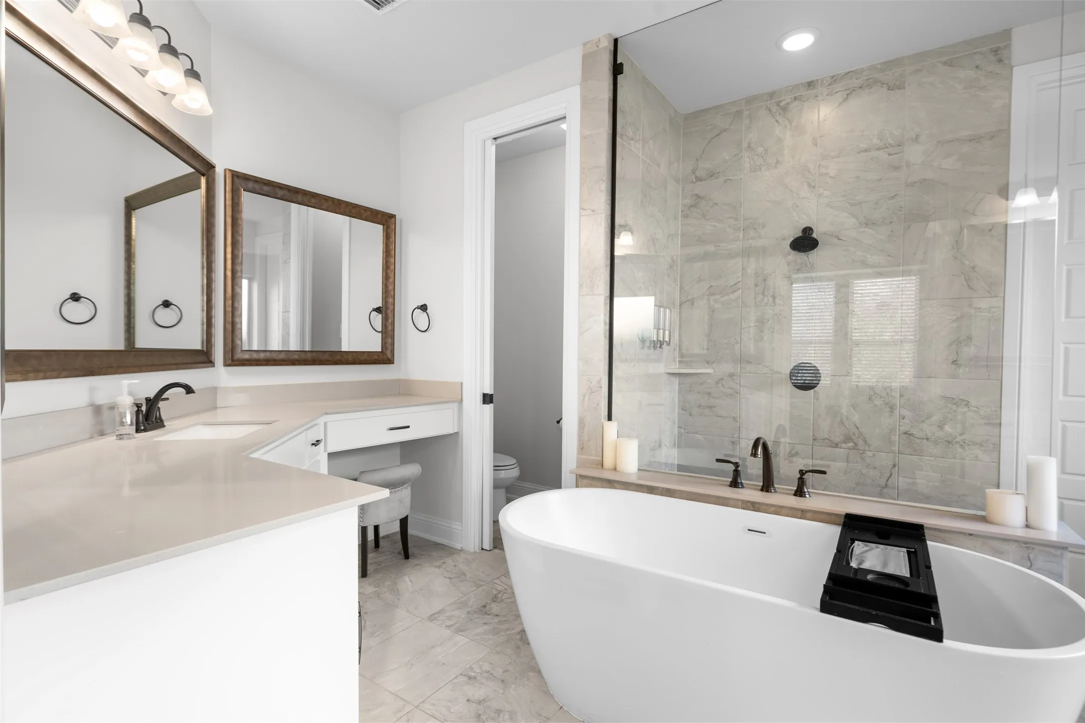 Freestanding soaking tub, walk-in shower with glass enclosure, dual vanity with undermount sinks, and built-in vanity desk