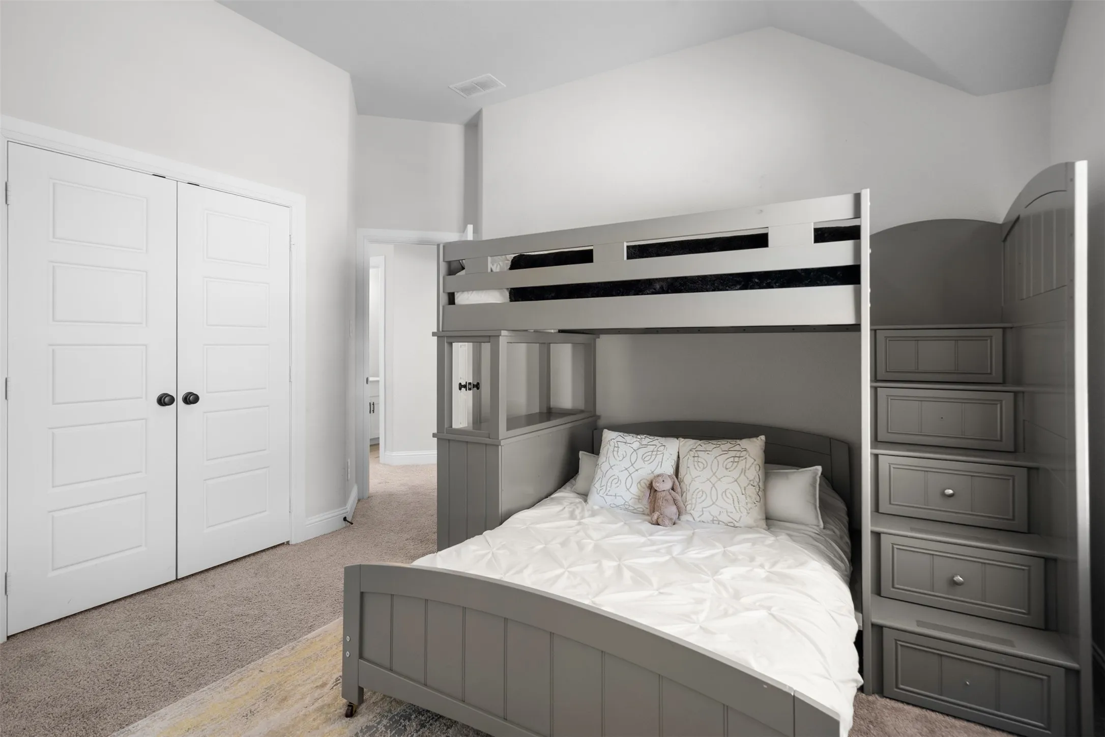 Vaulted ceiling, paneled closet doors with black hardware, and gray carpeting