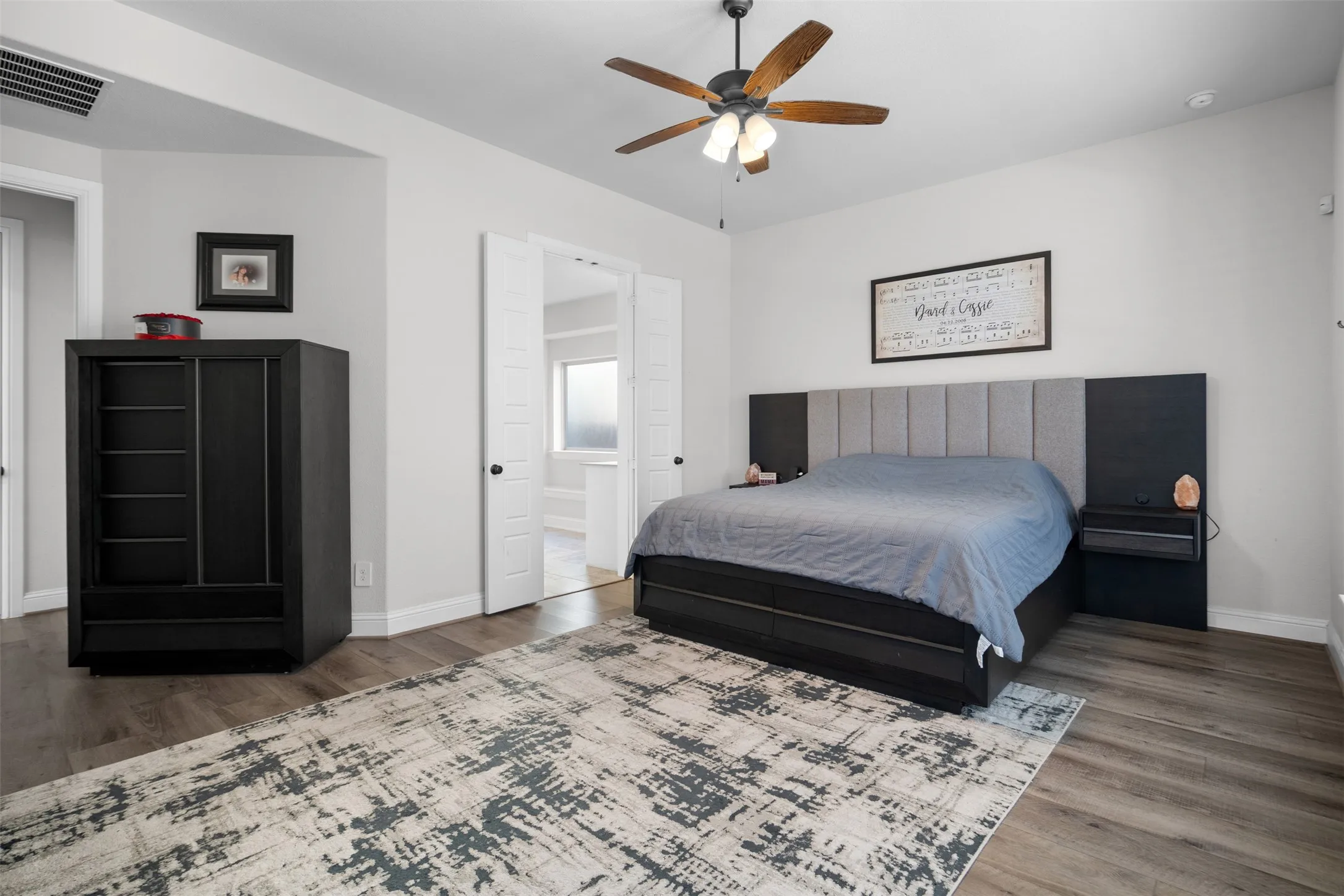 Wood-finish flooring, ceiling fan with integrated lighting, and light gray wall paint