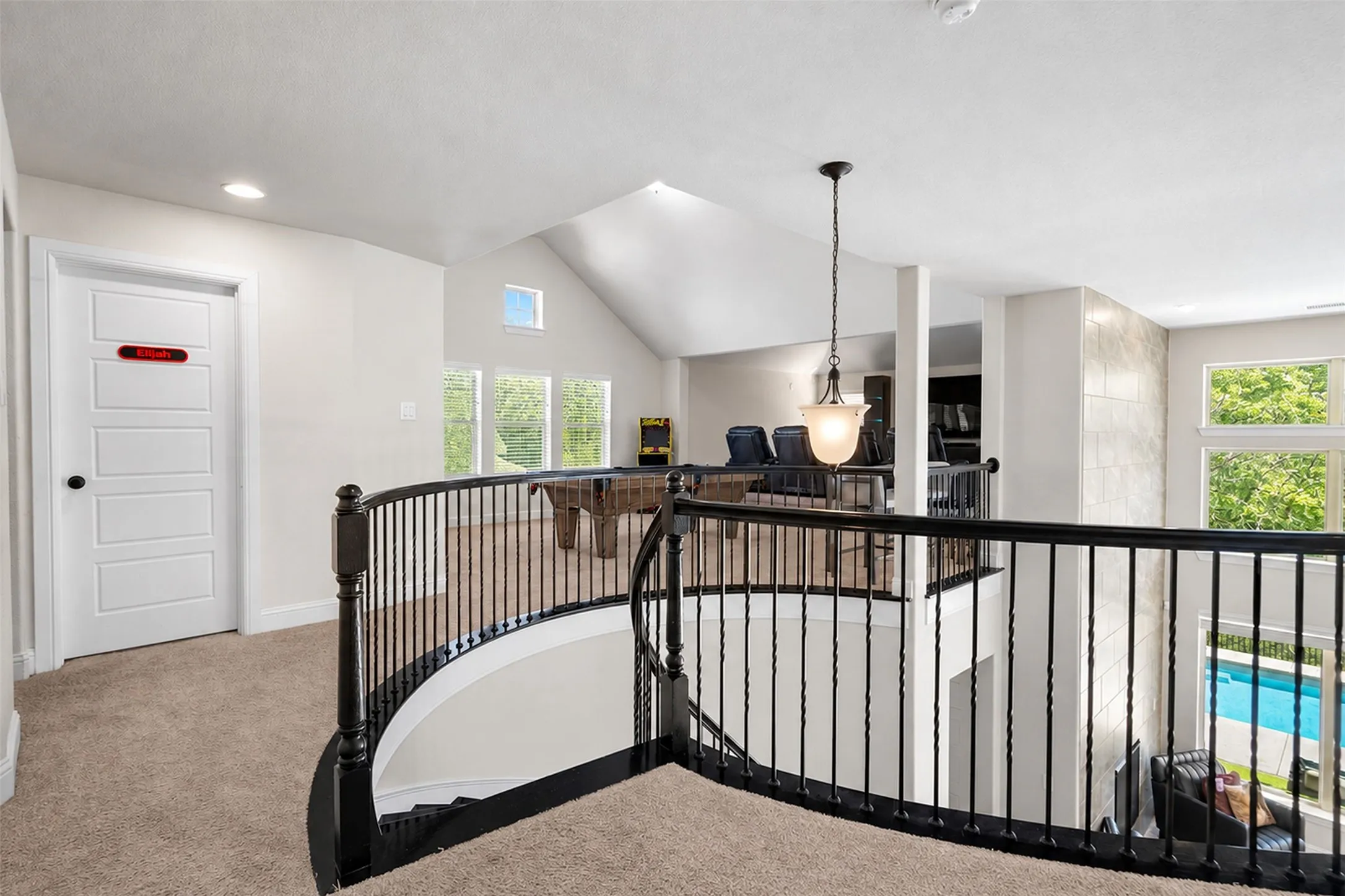 Open loft area featuring a vaulted ceiling with skylight, recessed lighting, and a decorative pendant light fixture