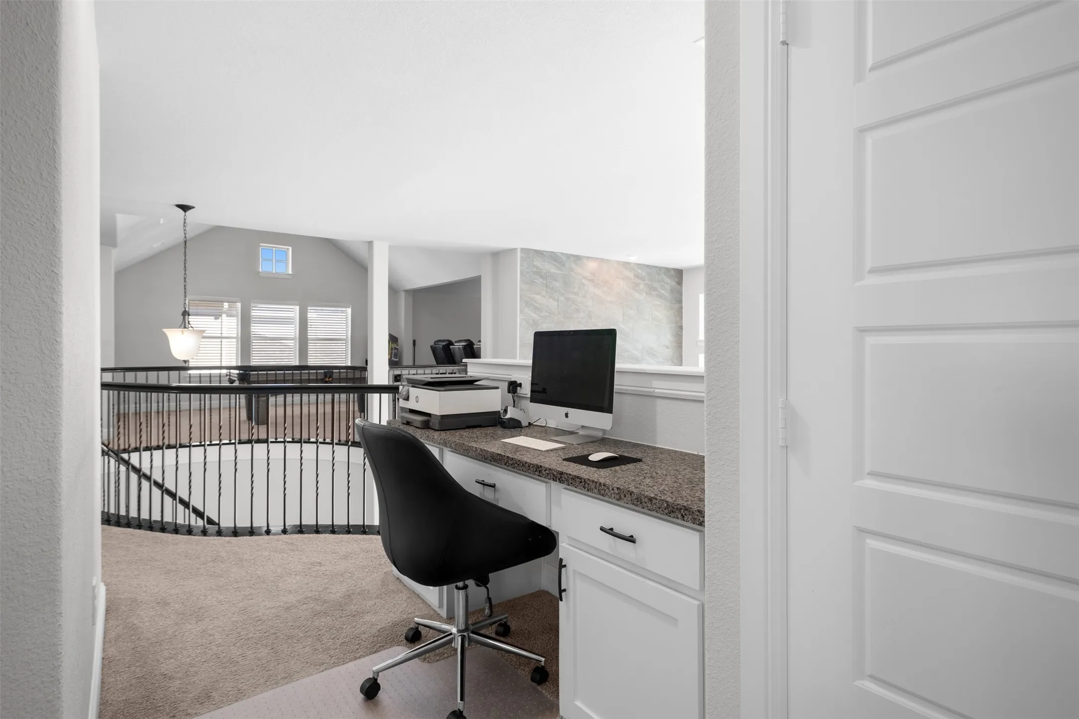 Built-in desk with a speckled countertop and white cabinetry