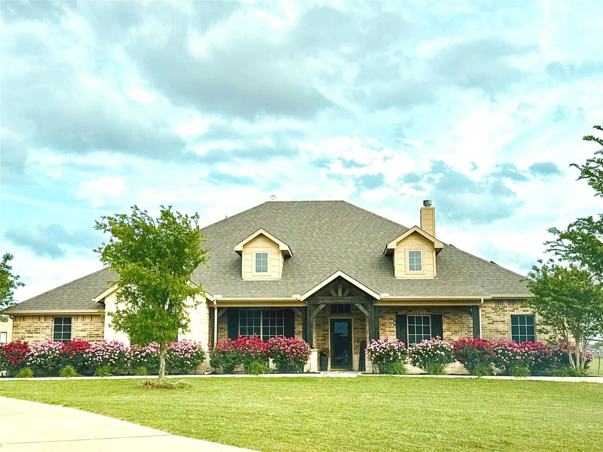 Brick exterior with dormer windows, a covered entry, and a symmetrical facade