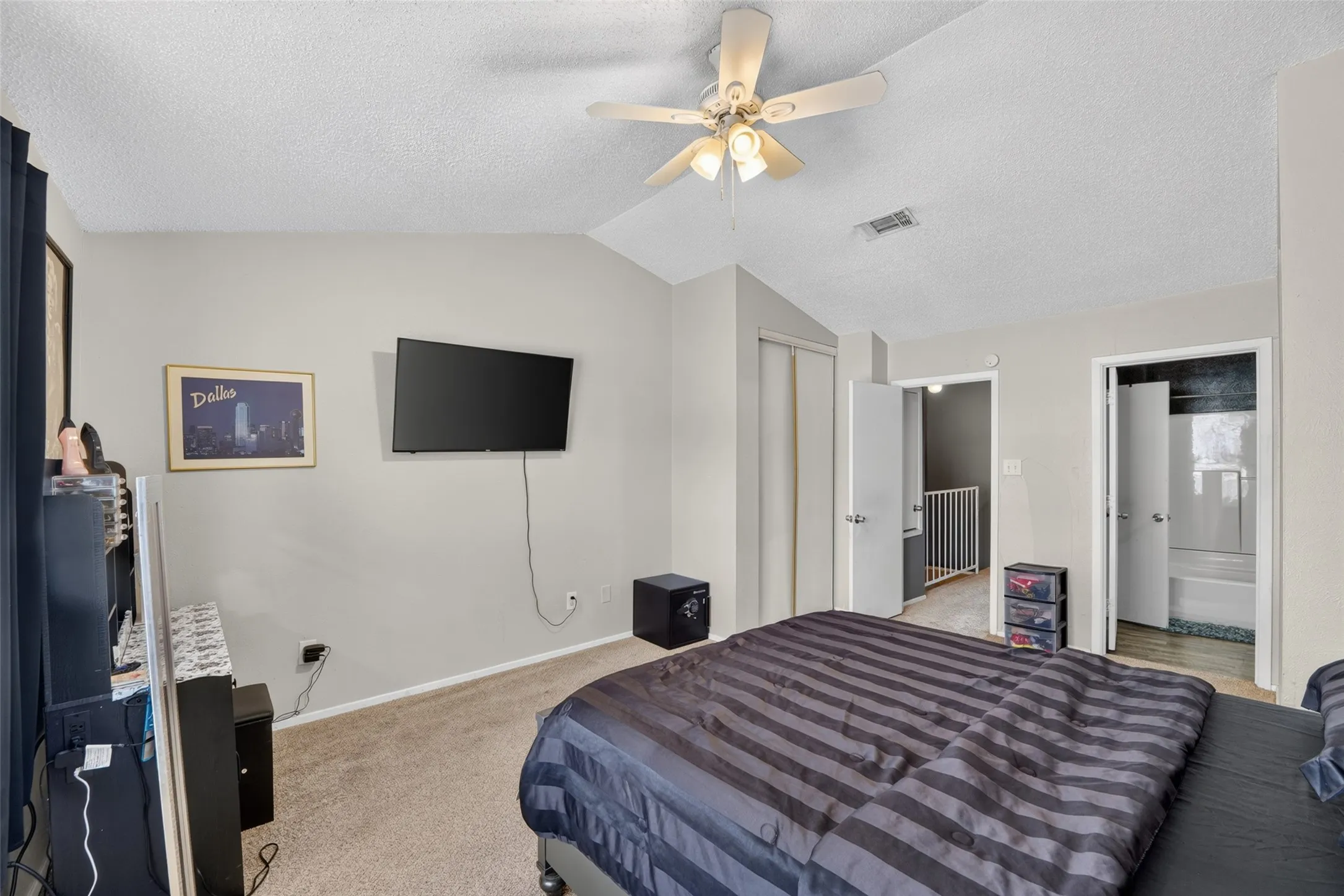 Angled ceiling with a built-in ceiling fan, light-toned wall paint, and plush carpet flooring