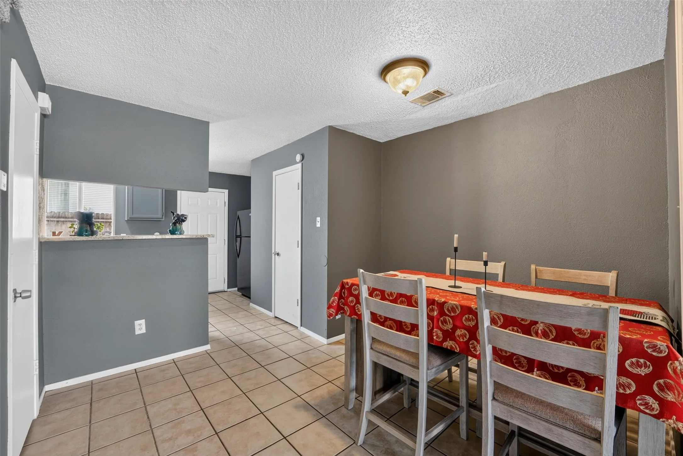 Tile flooring, painted walls, ceiling-mounted light fixture, and a pass-through counter with a stone-finish surface