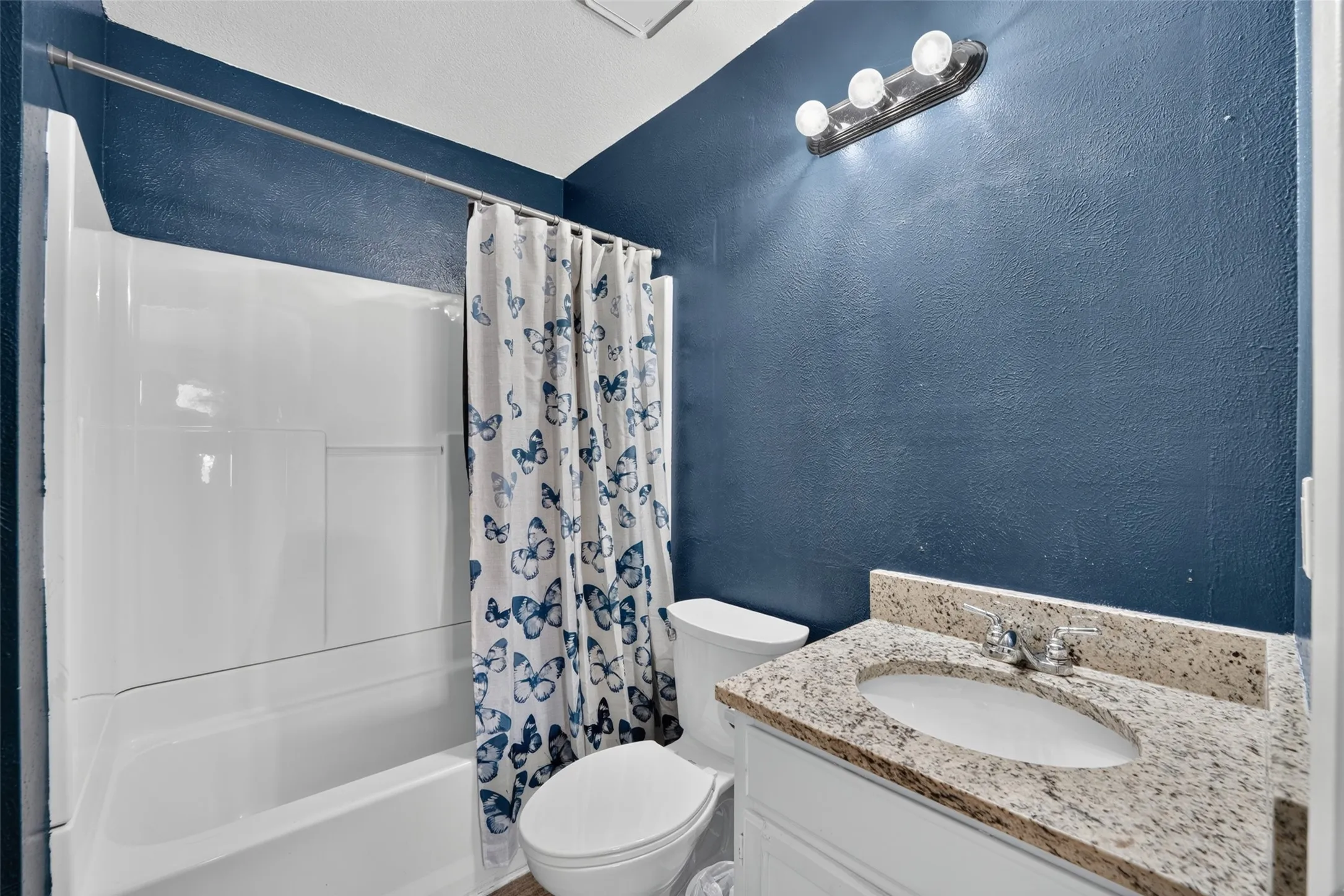 White vanity with a granite-style countertop and an undermount sink