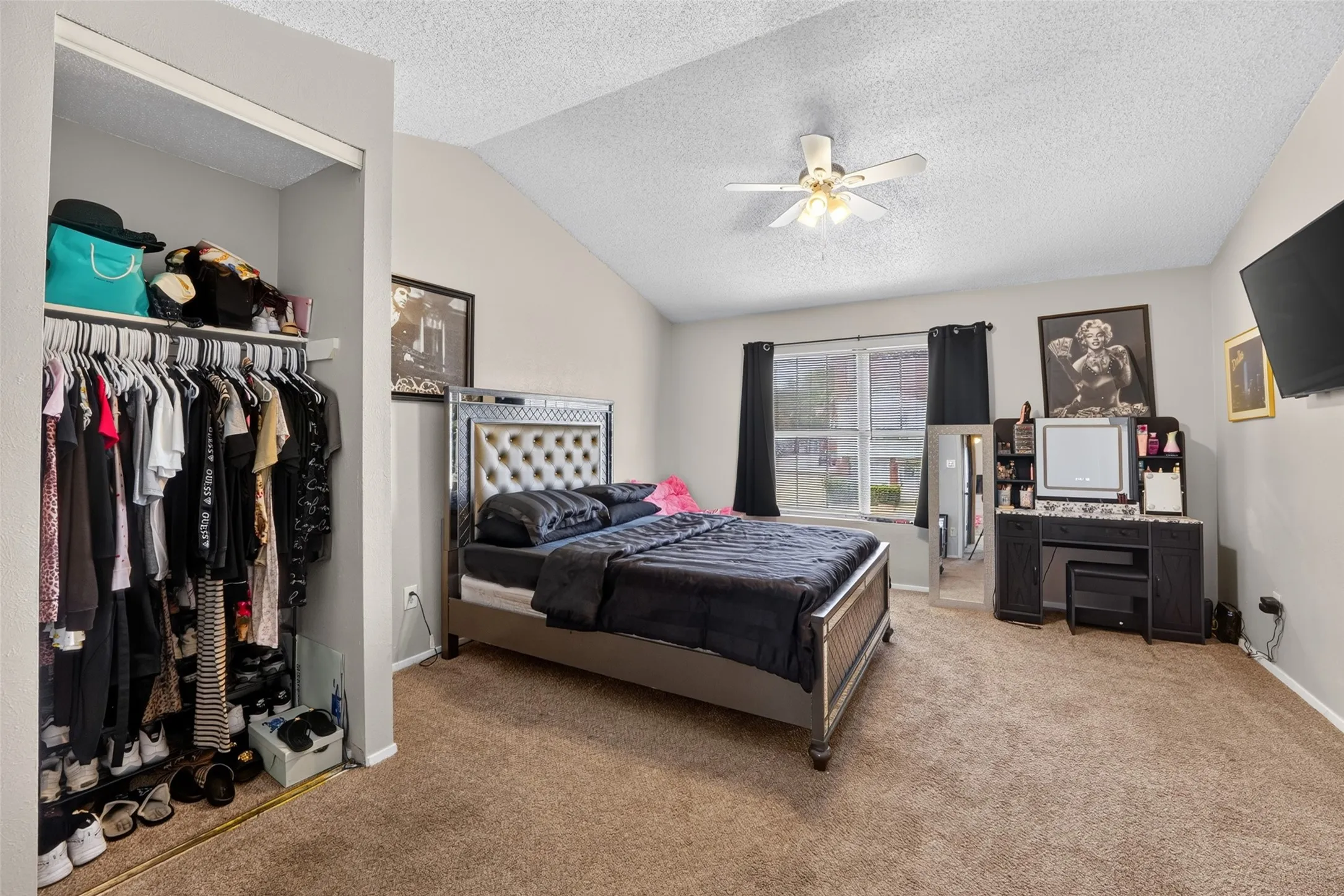 Vaulted ceiling, ceiling fan with integrated lighting, carpeted flooring, window with blinds, and an open closet