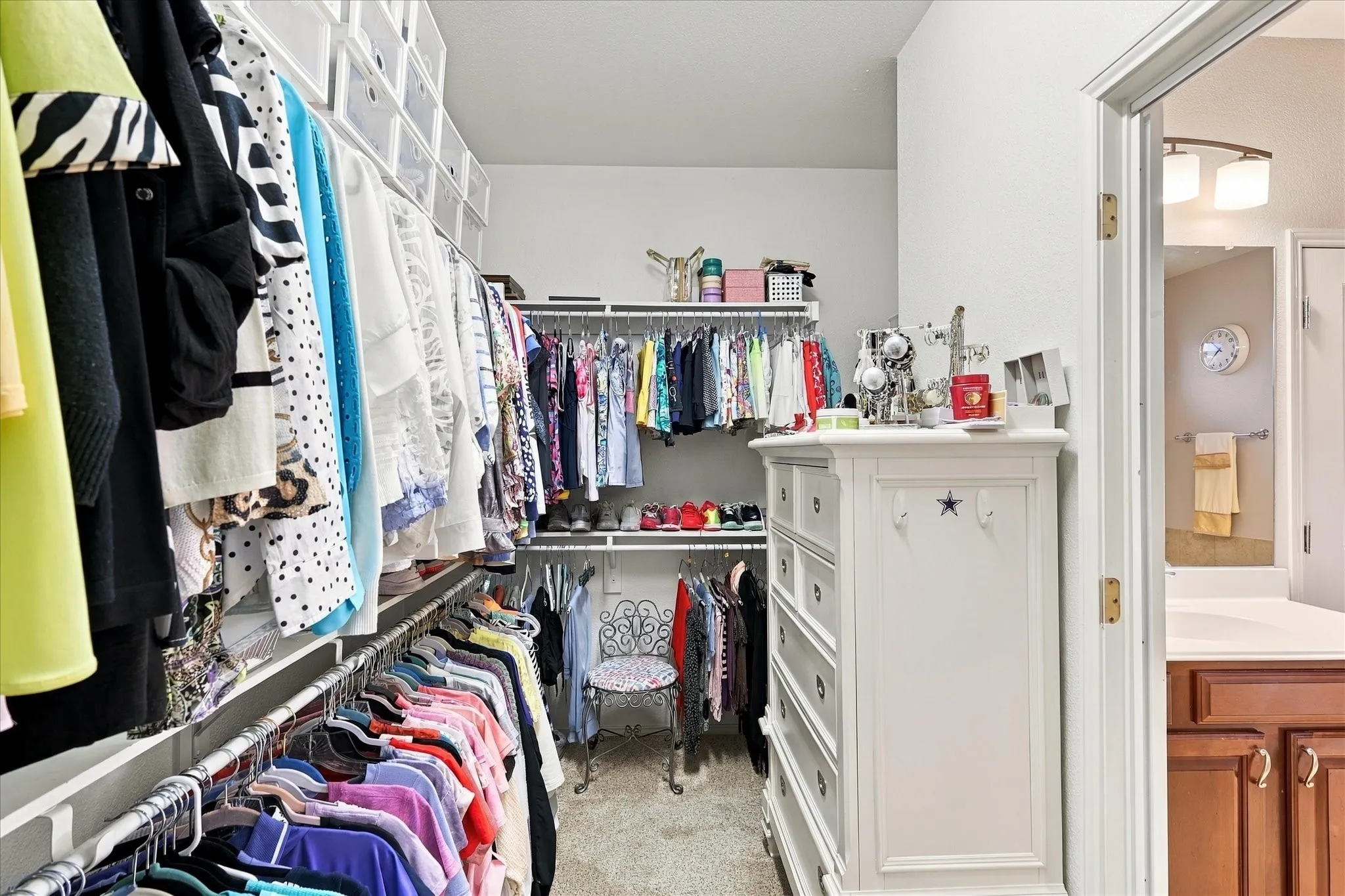 Walk-in closet featuring extensive built-in shelving, multiple hanging rods, and neutral carpeting