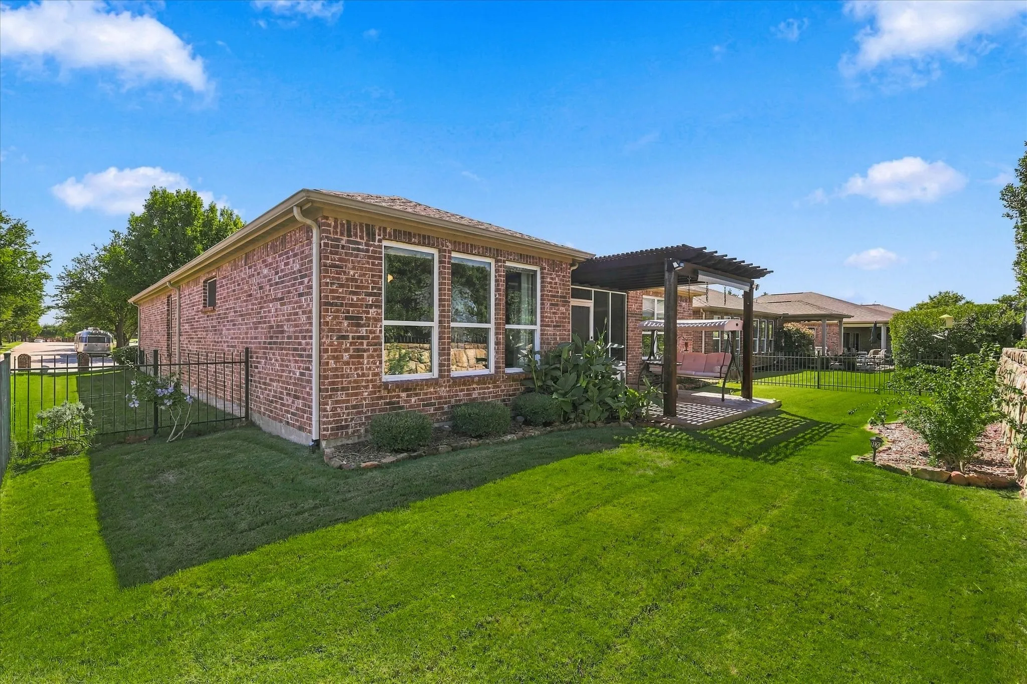 Brick exterior with multiple windows, leading to a back patio featuring a pergola