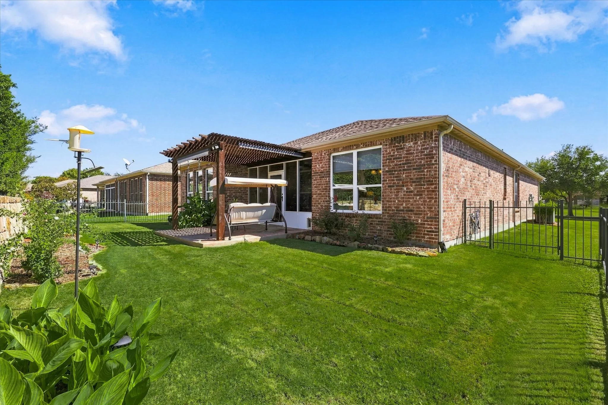 Brick exterior with a screened patio, wood pergola, and fully fenced backyard