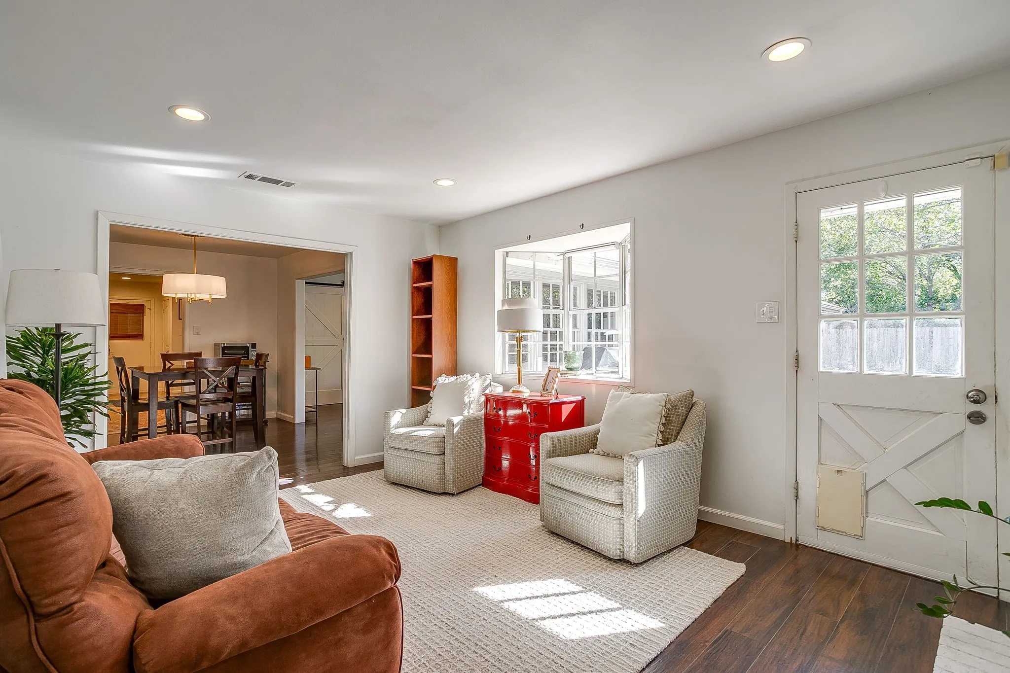 Bright, light-filled living room featuring recessed ceiling lighting, wood-finish flooring, and French doors with multiple panes opening to exterior access