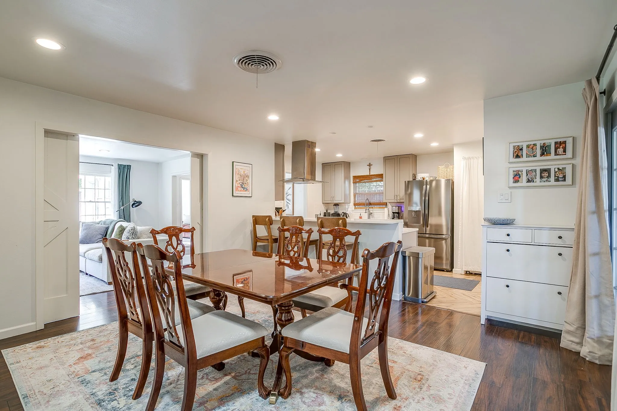 Elegant dining room featuring a round wood table, coordinating upholstered chairs, and hardwood flooring anchored by a neutral area rug