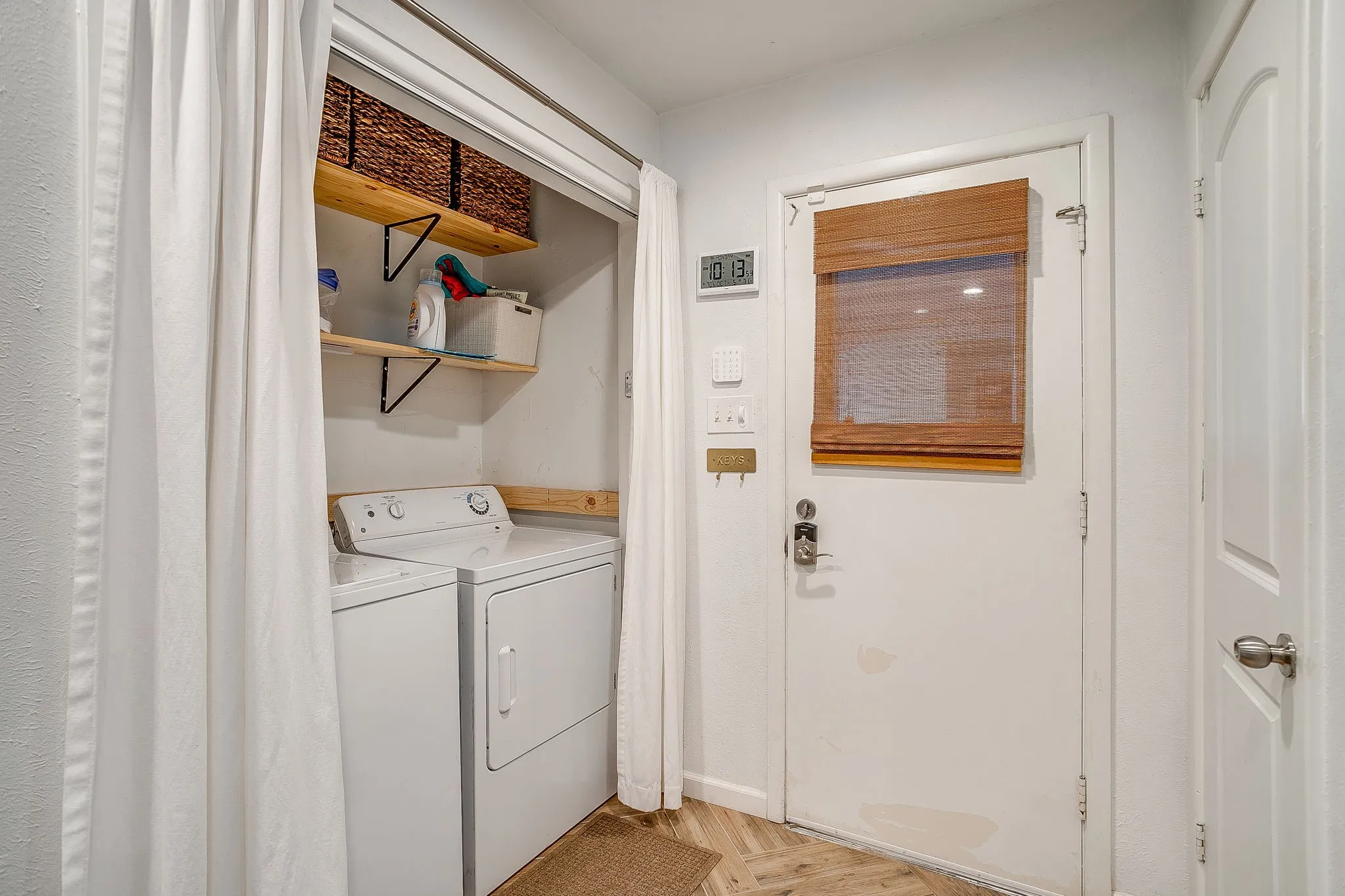 Dedicated laundry area with open shelving and white appliances