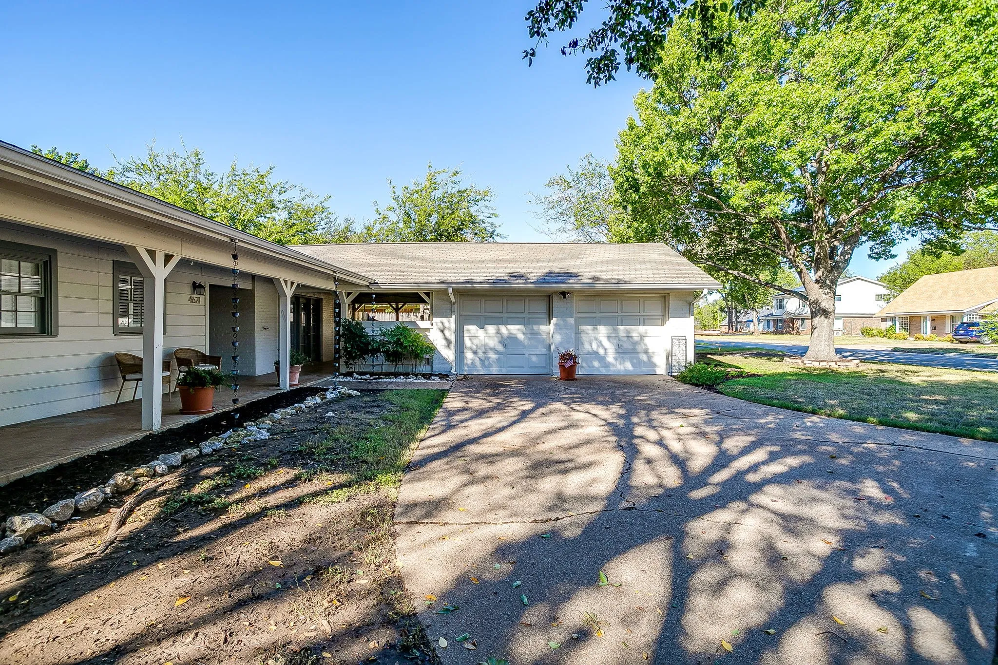 Exterior featuring a covered front porch, white siding, a two-car garage, and a concrete driveway