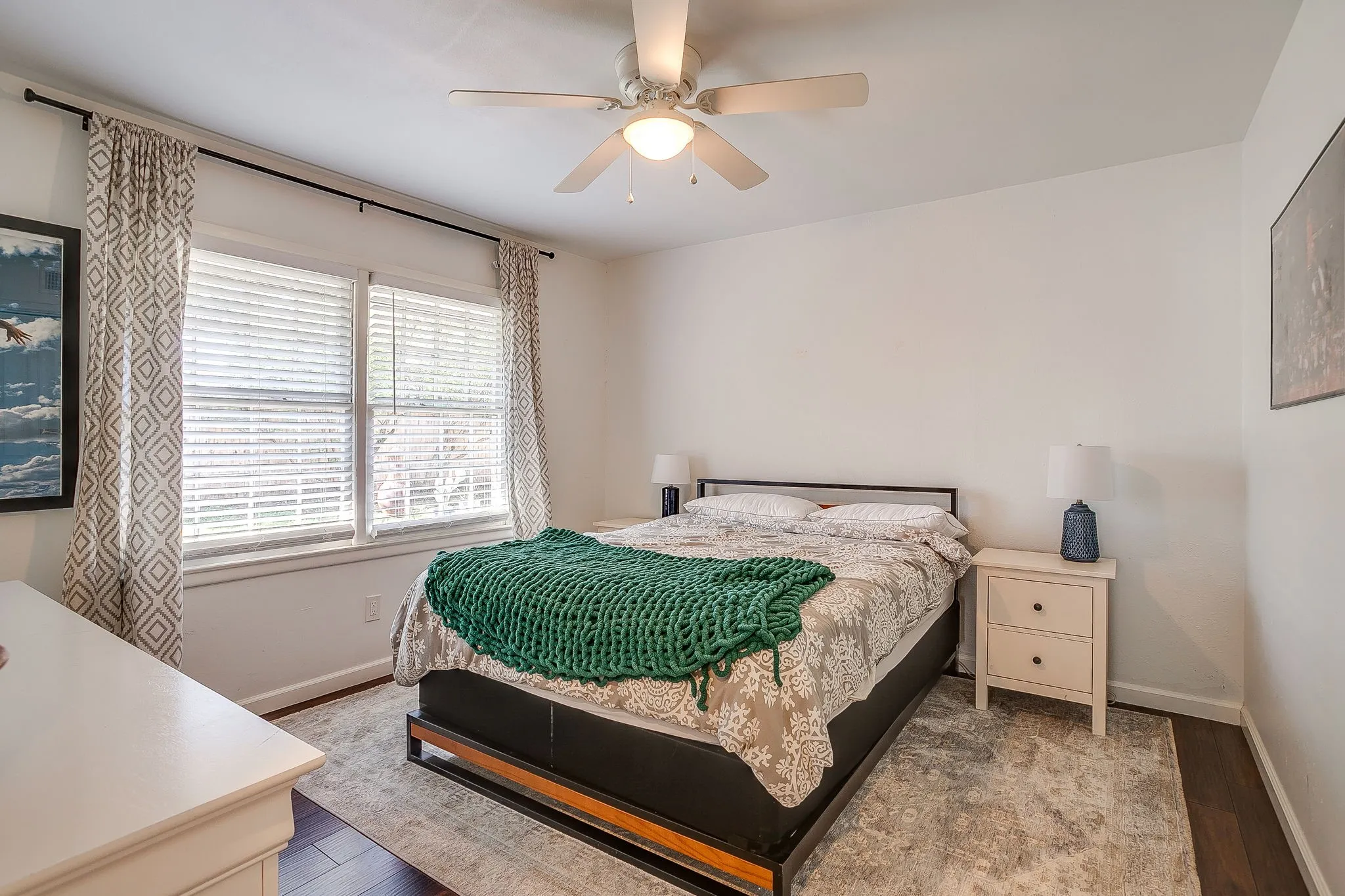 Bedroom featuring a ceiling fan, dual windows with blinds, and wood-finish flooring