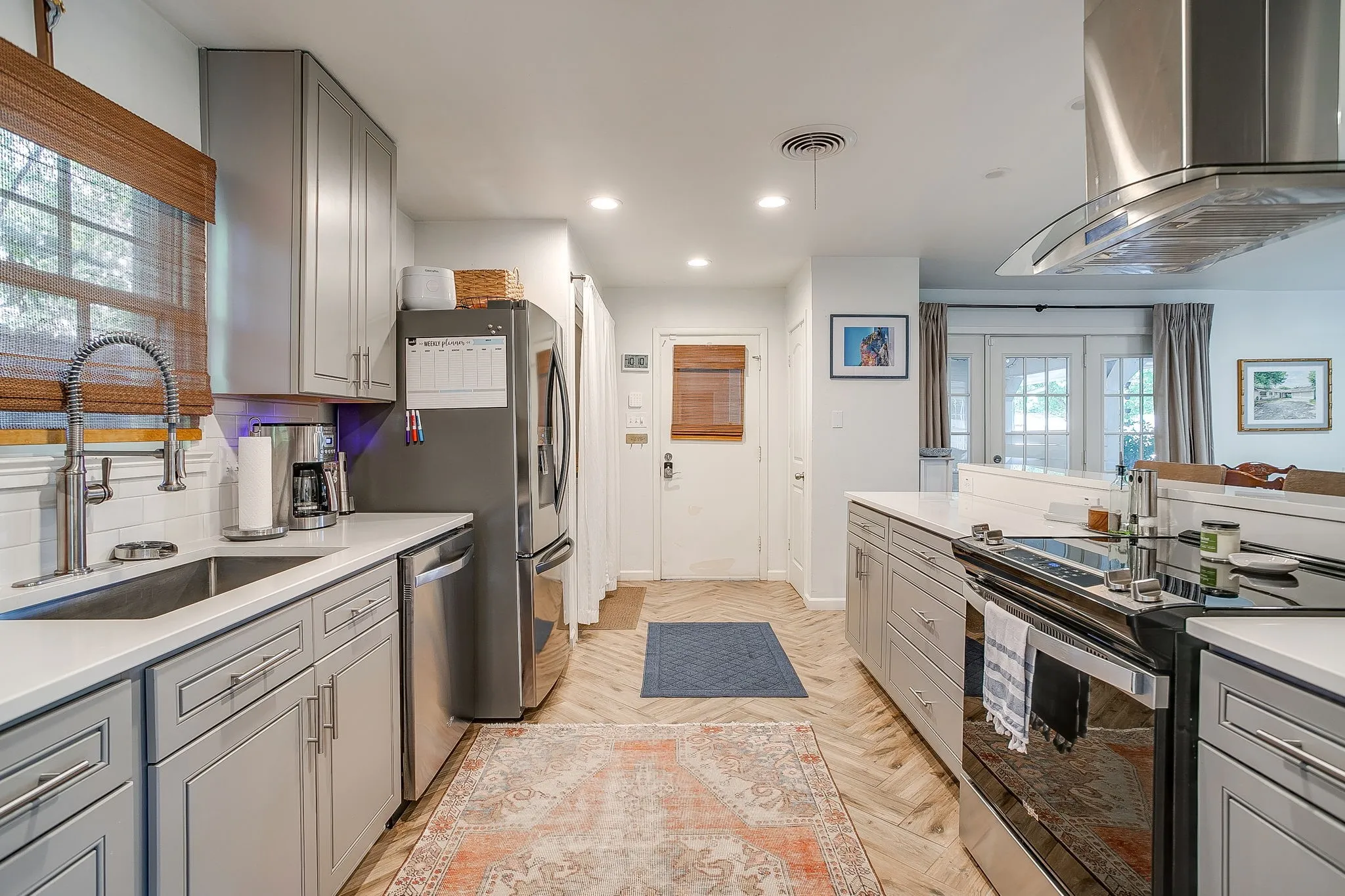 Stainless steel appliances, recessed lighting, light-toned cabinetry, light-toned countertops, and wood-finish flooring