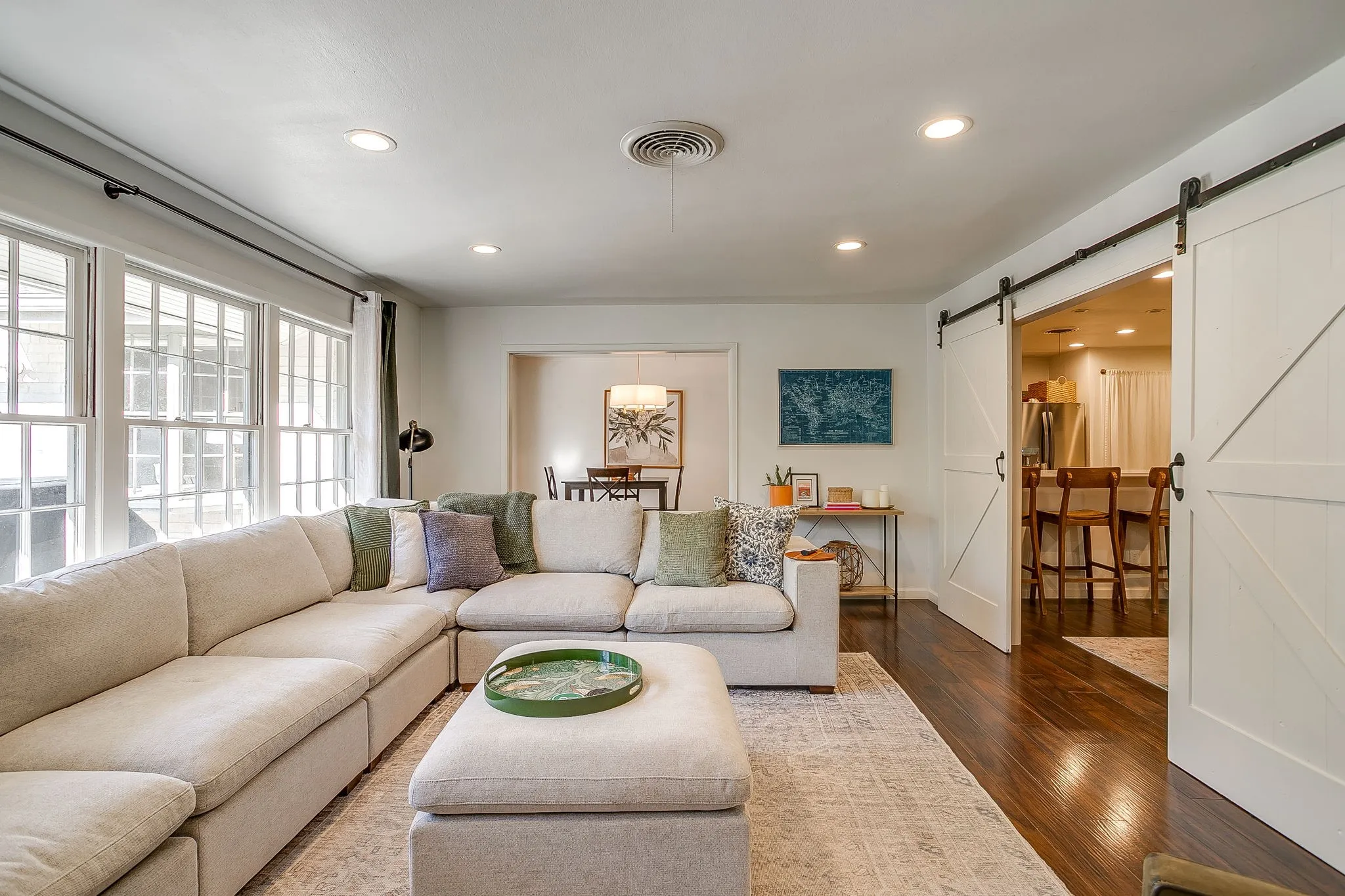 Wood-finish flooring, recessed lighting, and white barn doors on a black track