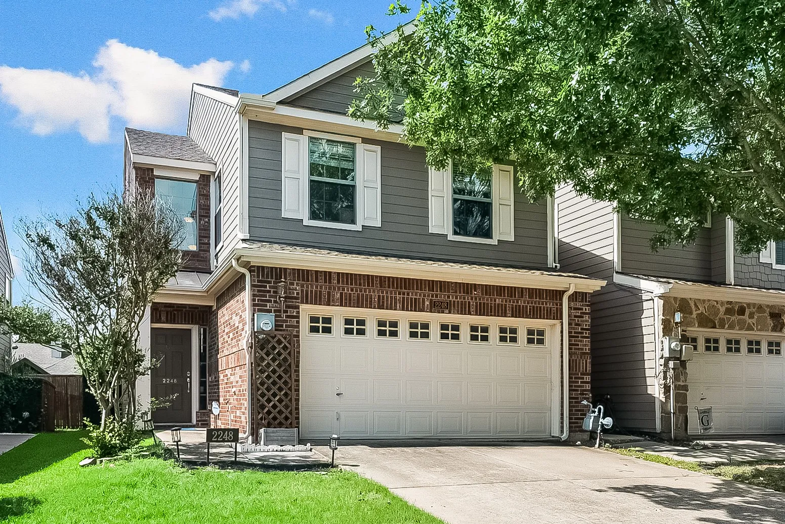 Two-story exterior with a brick and siding facade, an attached front-facing two-car garage, and a front entry door