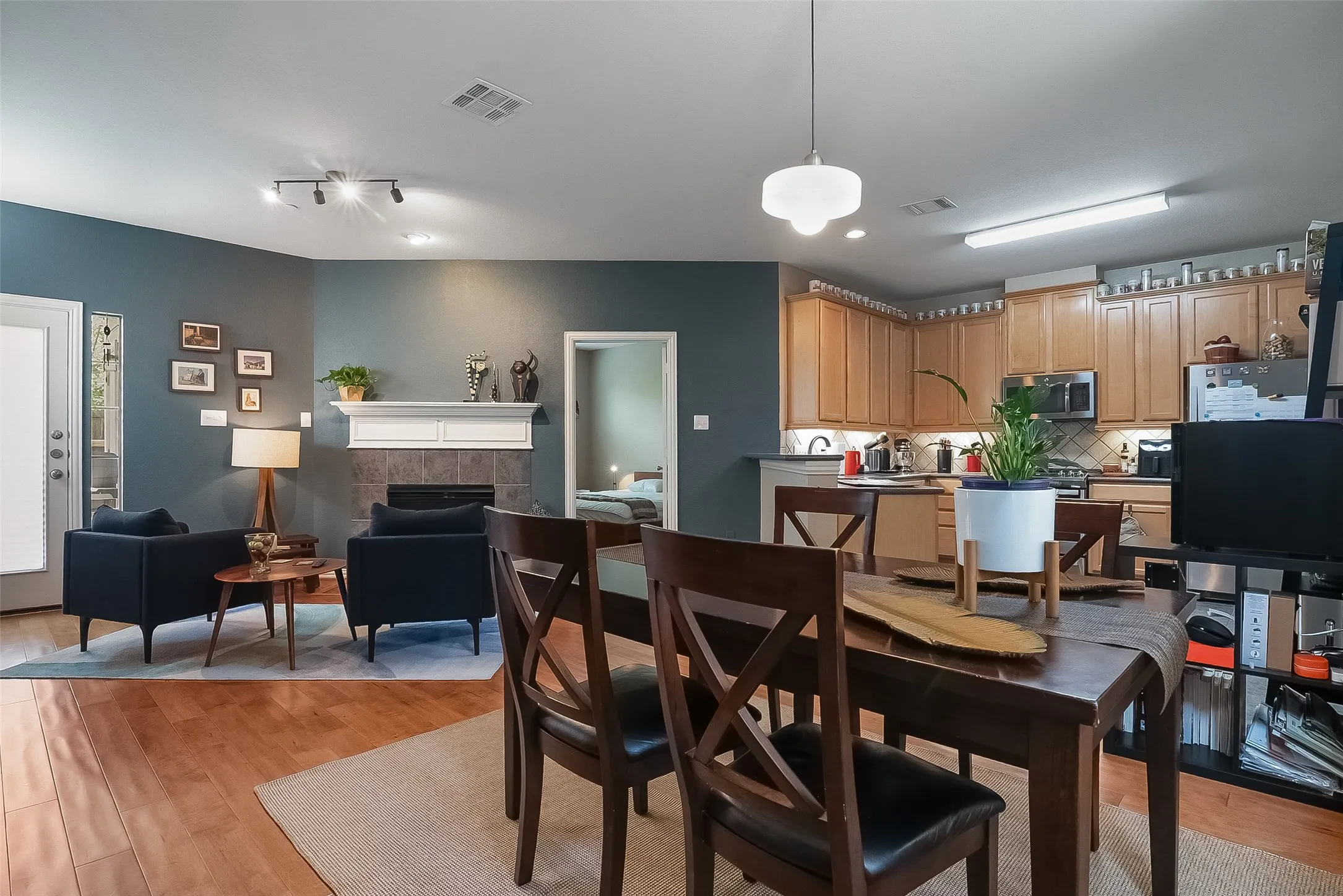 Open concept living space featuring wood-finish flooring, a fireplace with a tile surround and mantel, and track lighting