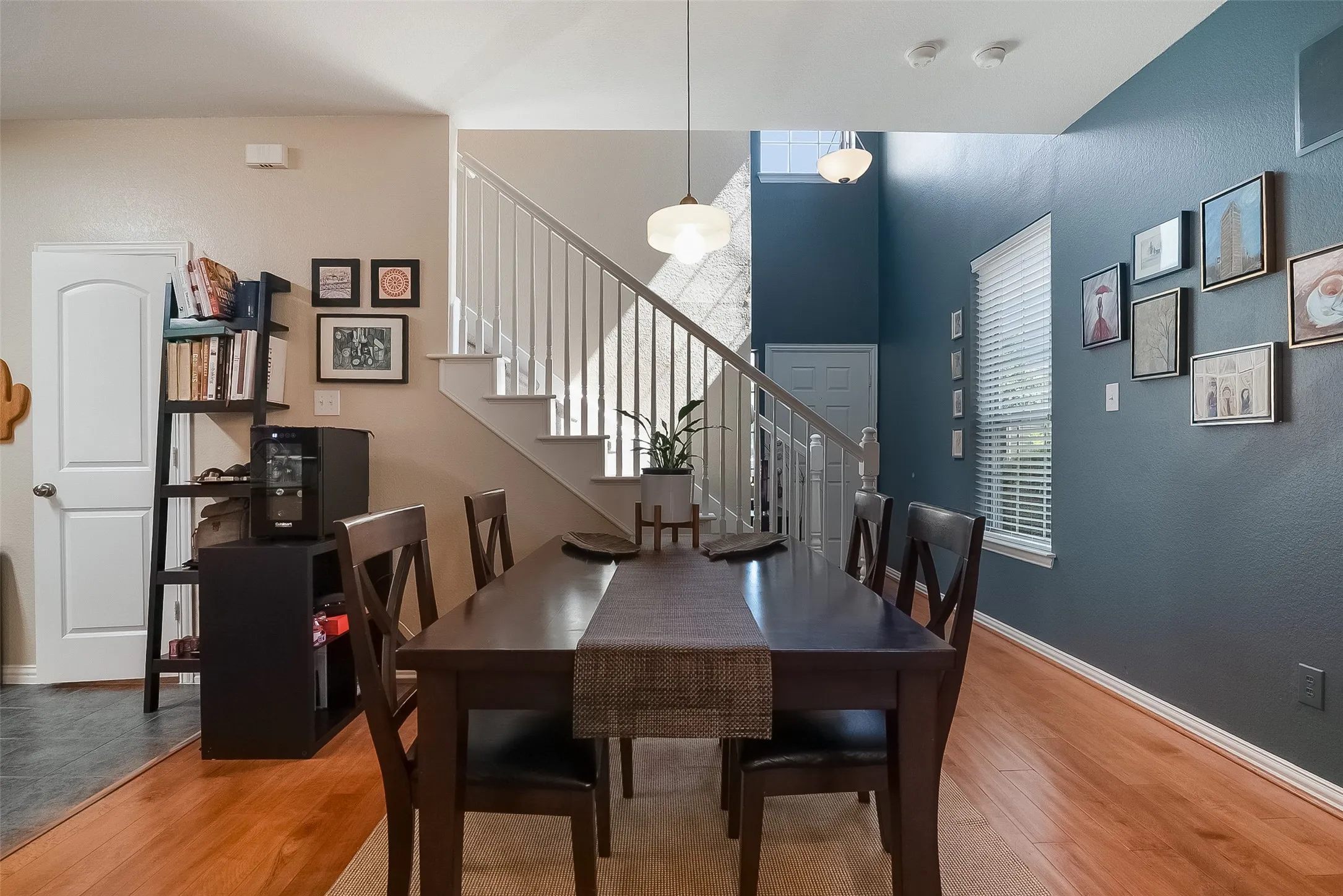 Hardwood-style flooring throughout, with a white spindle staircase and a two-story accent wall