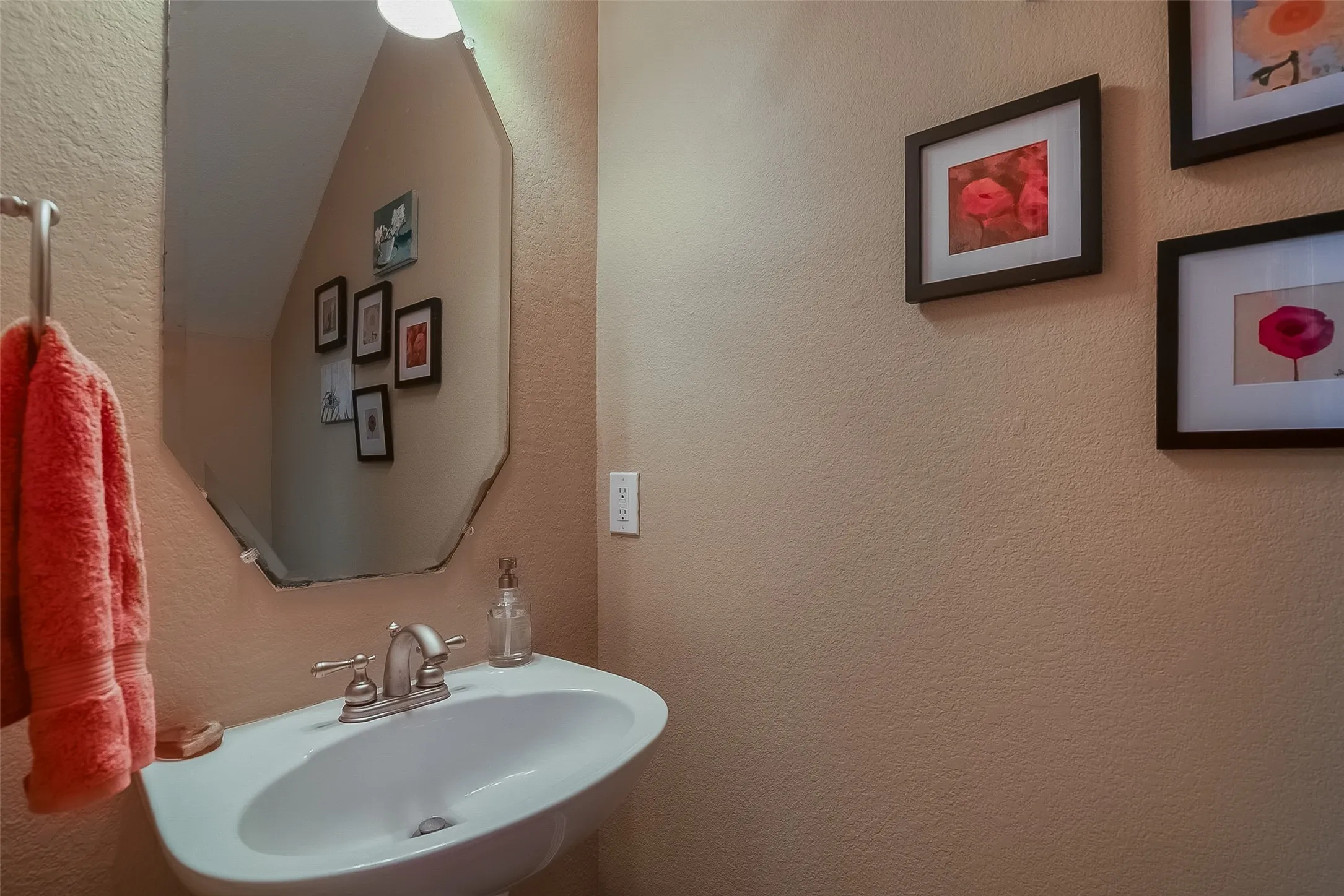 Pedestal sink with brushed nickel faucet, wall-mounted mirror, and overhead light fixture