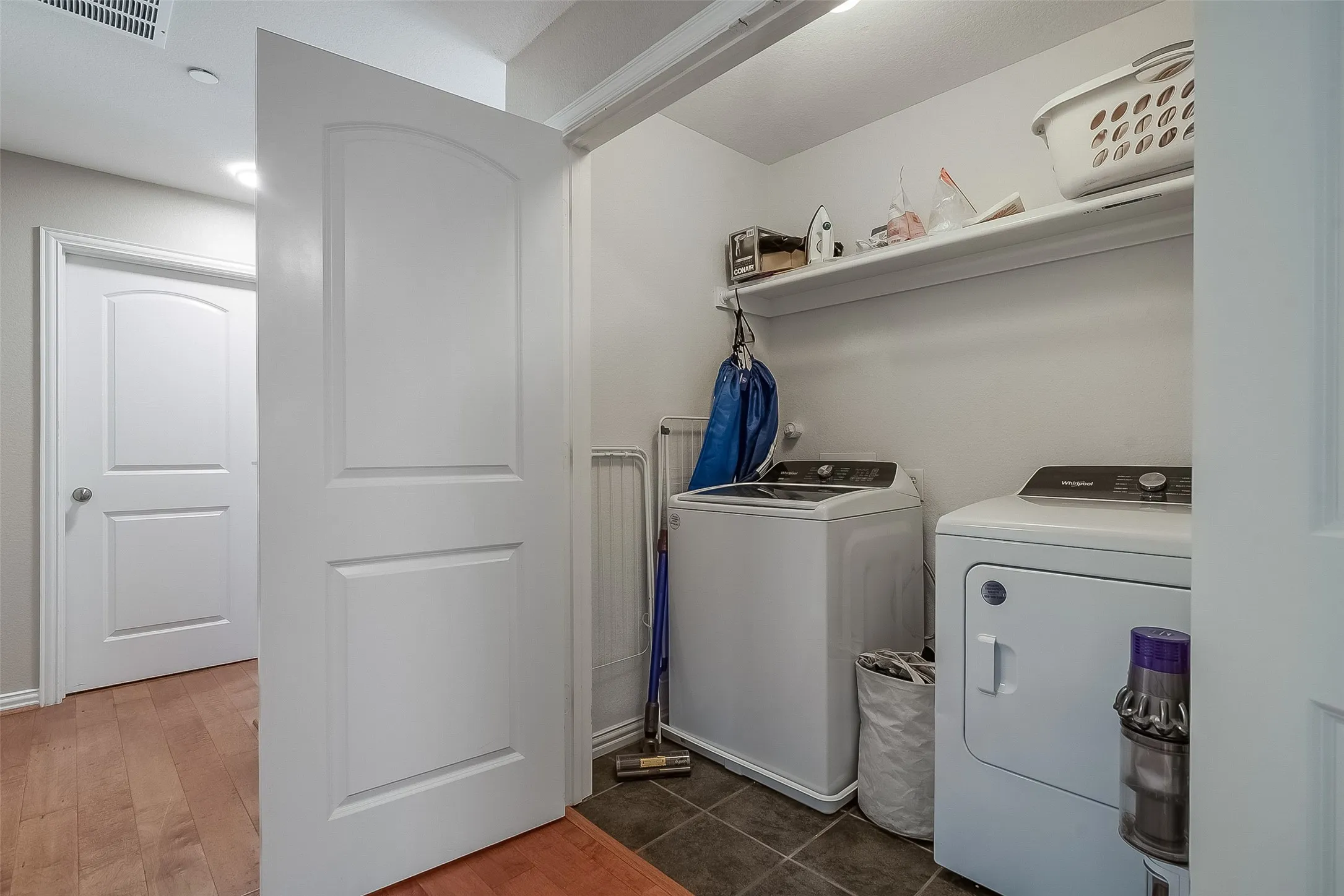 Laundry area featuring a side-by-side washer and dryer, a wall-mounted storage shelf, and tile flooring