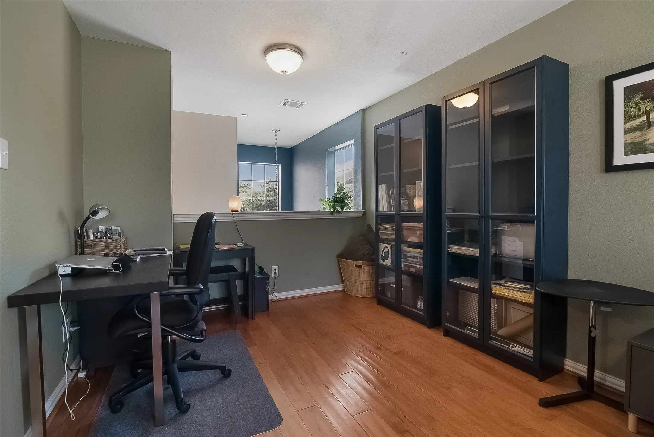 Hardwood flooring throughout, two built-in glass-front cabinets, and recessed lighting