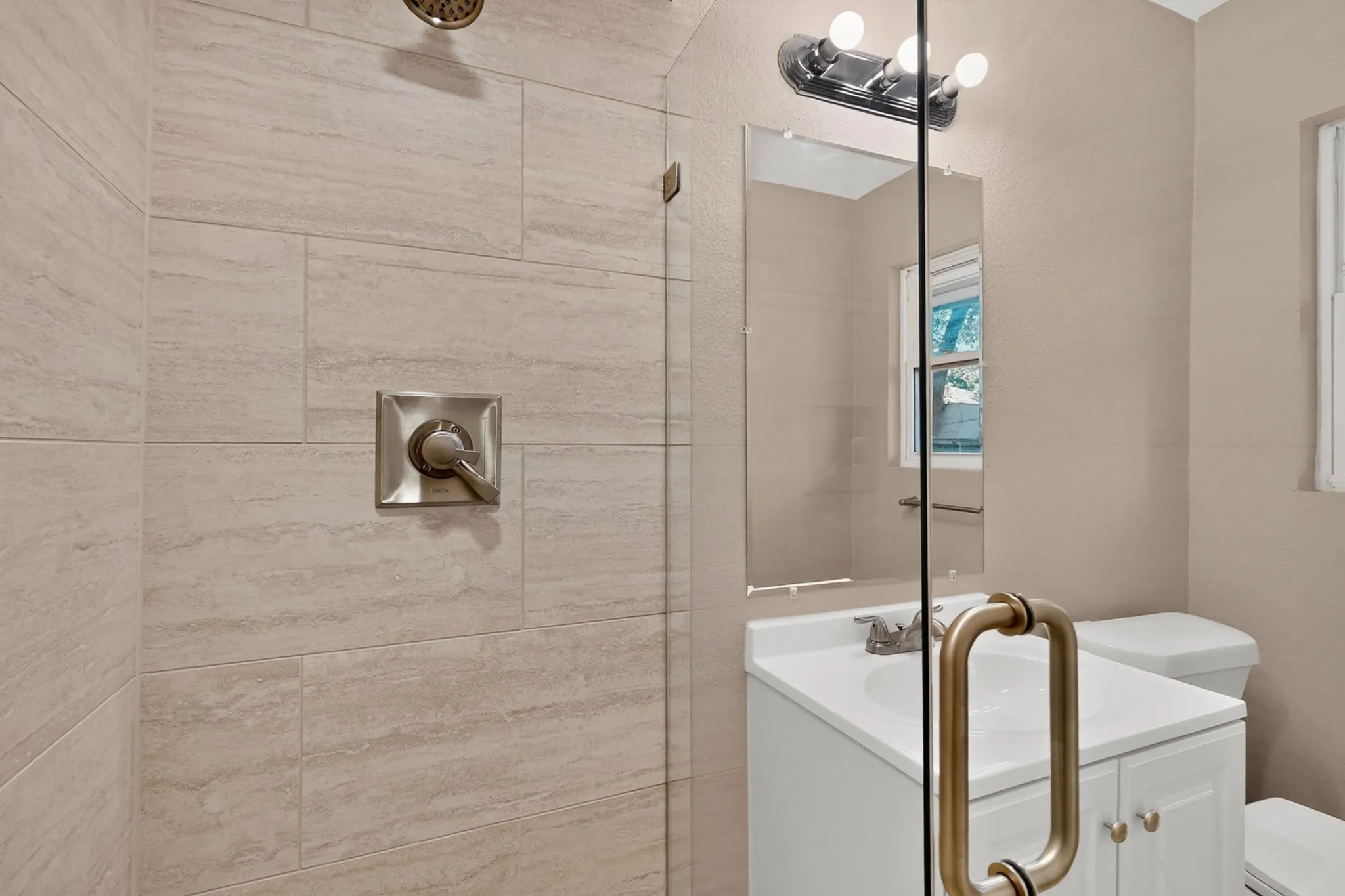Glass-enclosed shower with large format wall tiling and brushed nickel fixtures