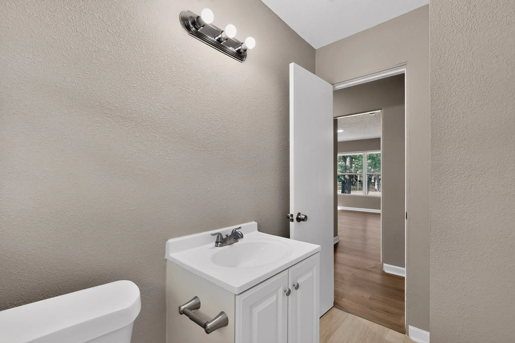 White vanity with a single basin sink, chrome faucet, and brushed nickel hardware