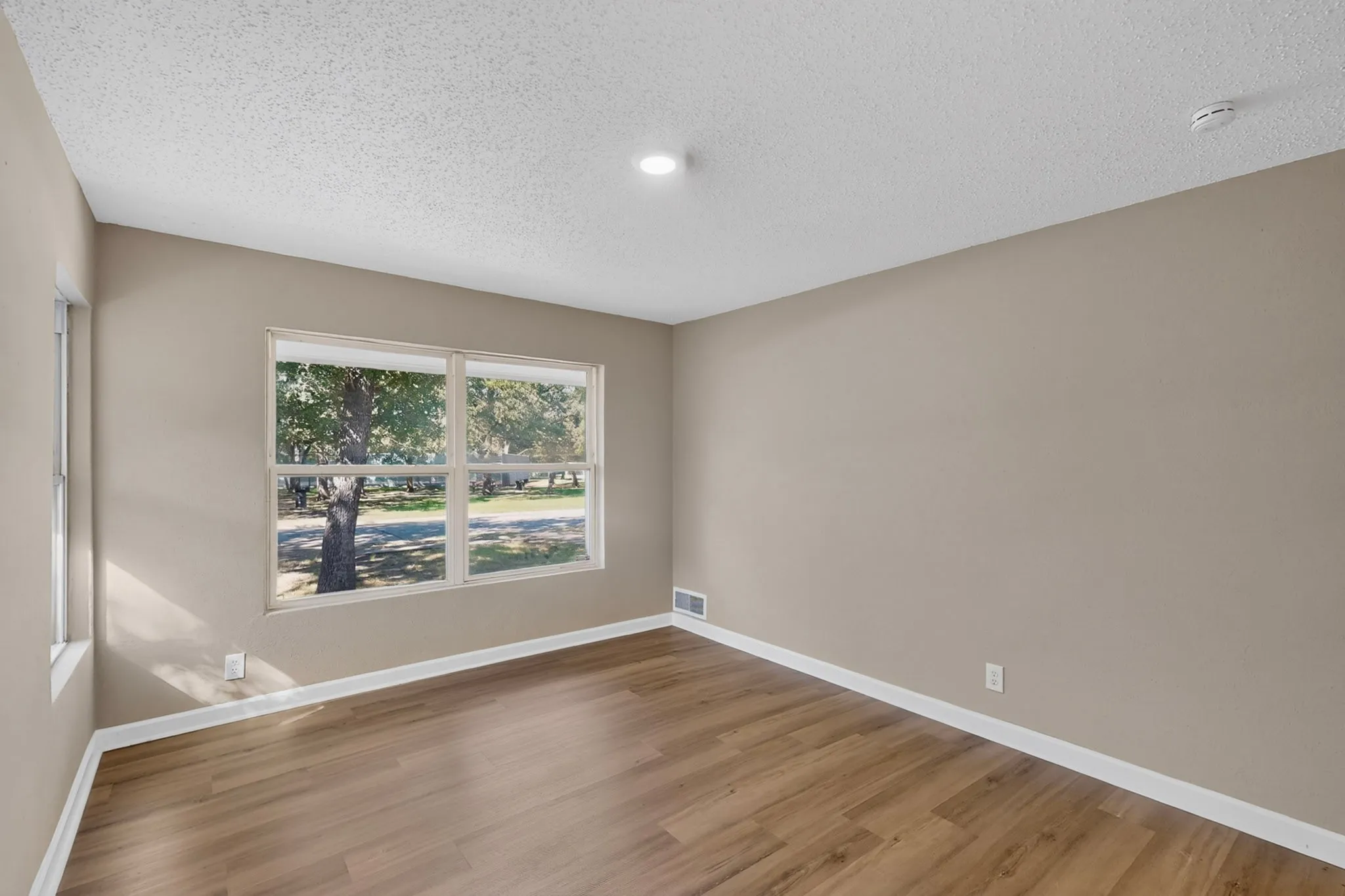 Wood-finish flooring, neutral wall tones, white trim, and a large multi-pane window