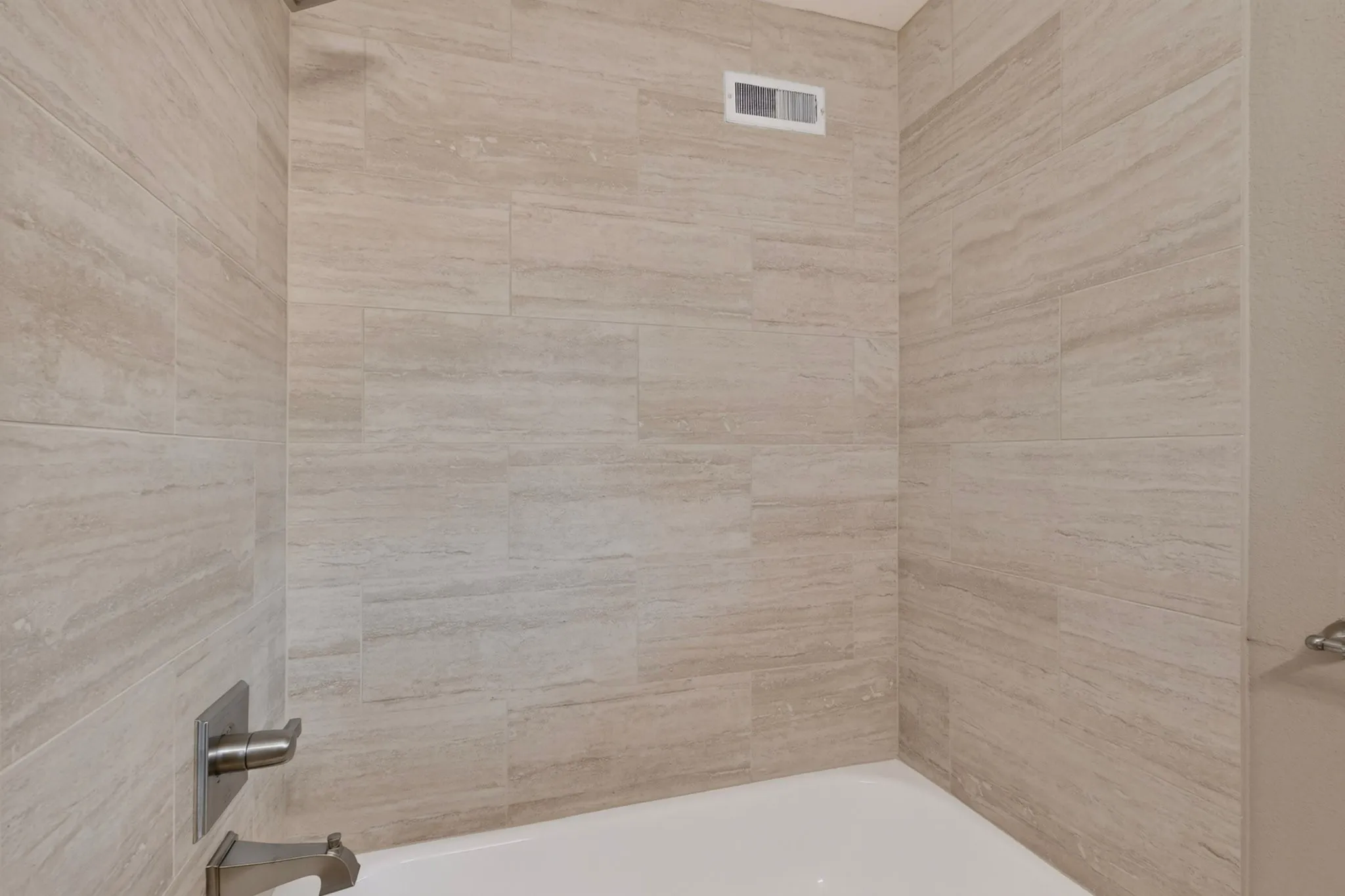 Tub shower with large format tile surround and brushed nickel fixtures